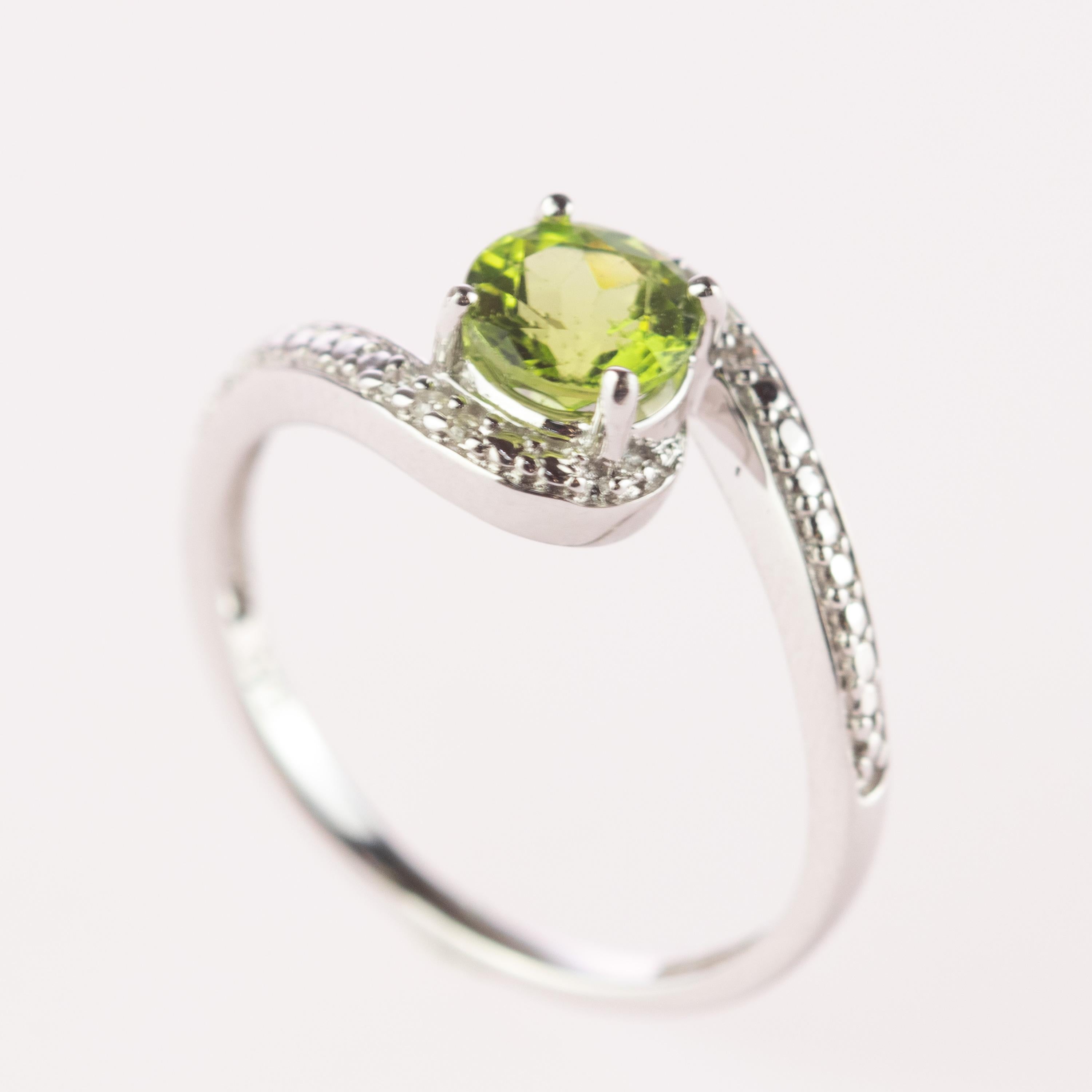 Round faceted cut contrarie ring design. 1 carat shining peridot on 9 karat white gold acompanied by sparkling diamonds. This ring is inspired by the colours of South Italy's Winter Trees. With a perfect size, it will fill with your daily elegant