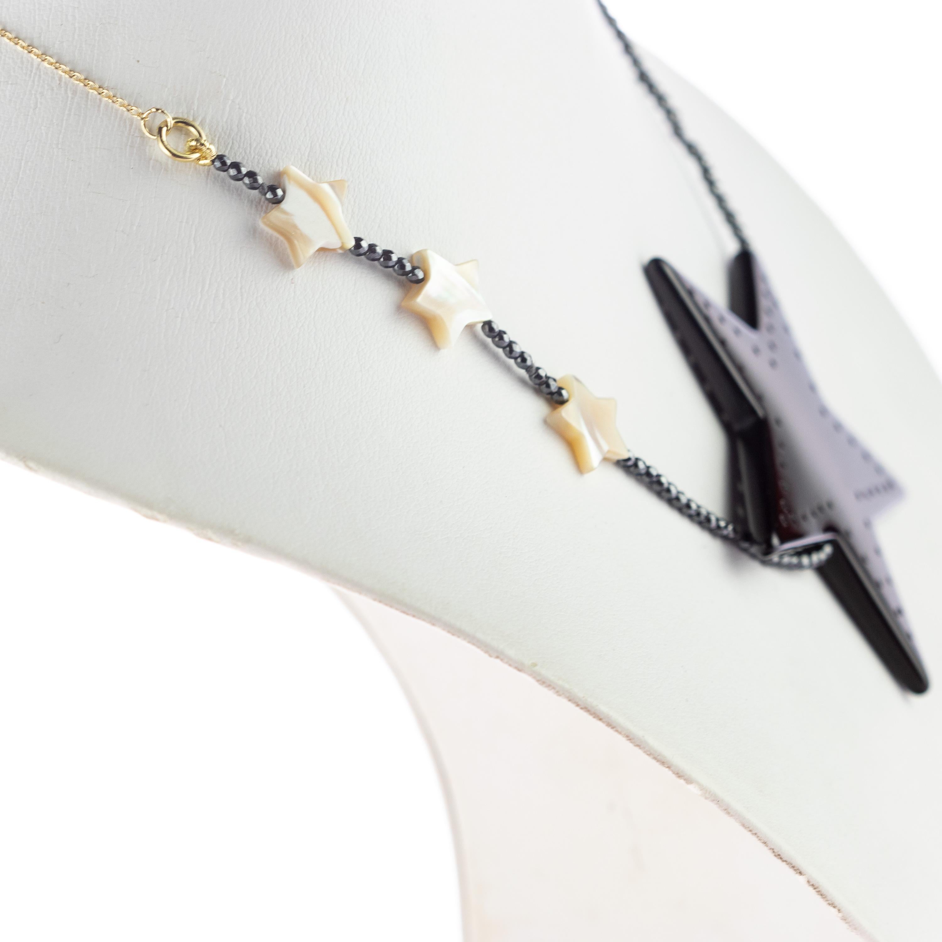 Meravigliosa collana con stelle di madreperla accompagnate da piccole sfere di ematite e da una bellissima grande stella di agata nera per un fascino luminoso e unico. Gioiello luminoso con gioielli preziosi naturali su un'elegante montatura in oro