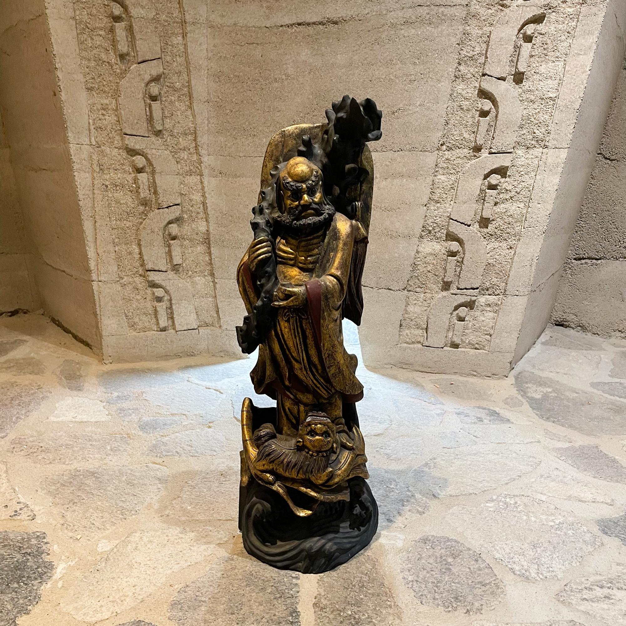 Intricately carved wood sculpture Chinese Immortal Longevity Buddha Deity figure crafted with gold gilt and a black finish with foo dog at base.
Measures: 28.5 T x 7.5 D x 10 W inches
Original Preowned Vintage Unrestored Condition. 
Refer to