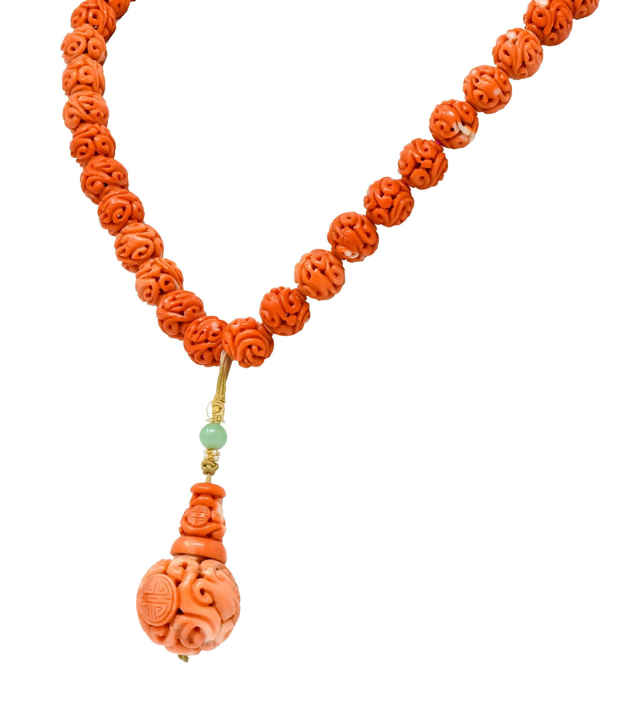 Necklace comprised of round coral beads, graduating in size from 8.0 mm to 11.50 mm, strung on a pink silk cord completed by a silver clasp

Each bead is intricately hand carved with a pierced, scrolling, dragon motif and displays varying tones of