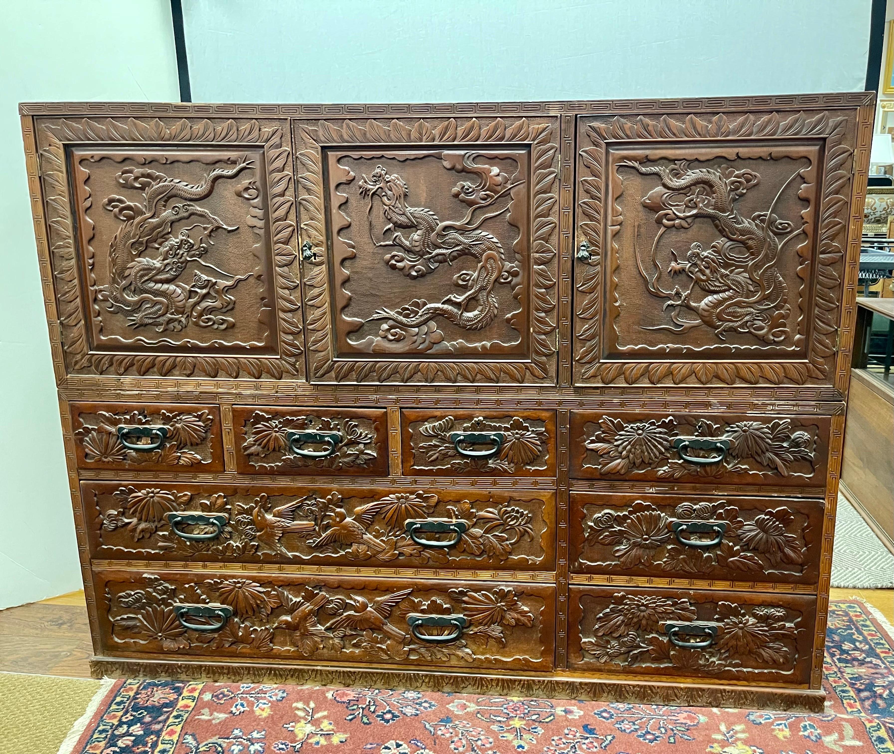 A stunning turn of the century two piece Chinese cabinet featuring a top and bottom. The carvings are throughout and richly detailed. There are multiple drawers and compartments throughout. The top piece fits nicely right on top of the bottom piece.