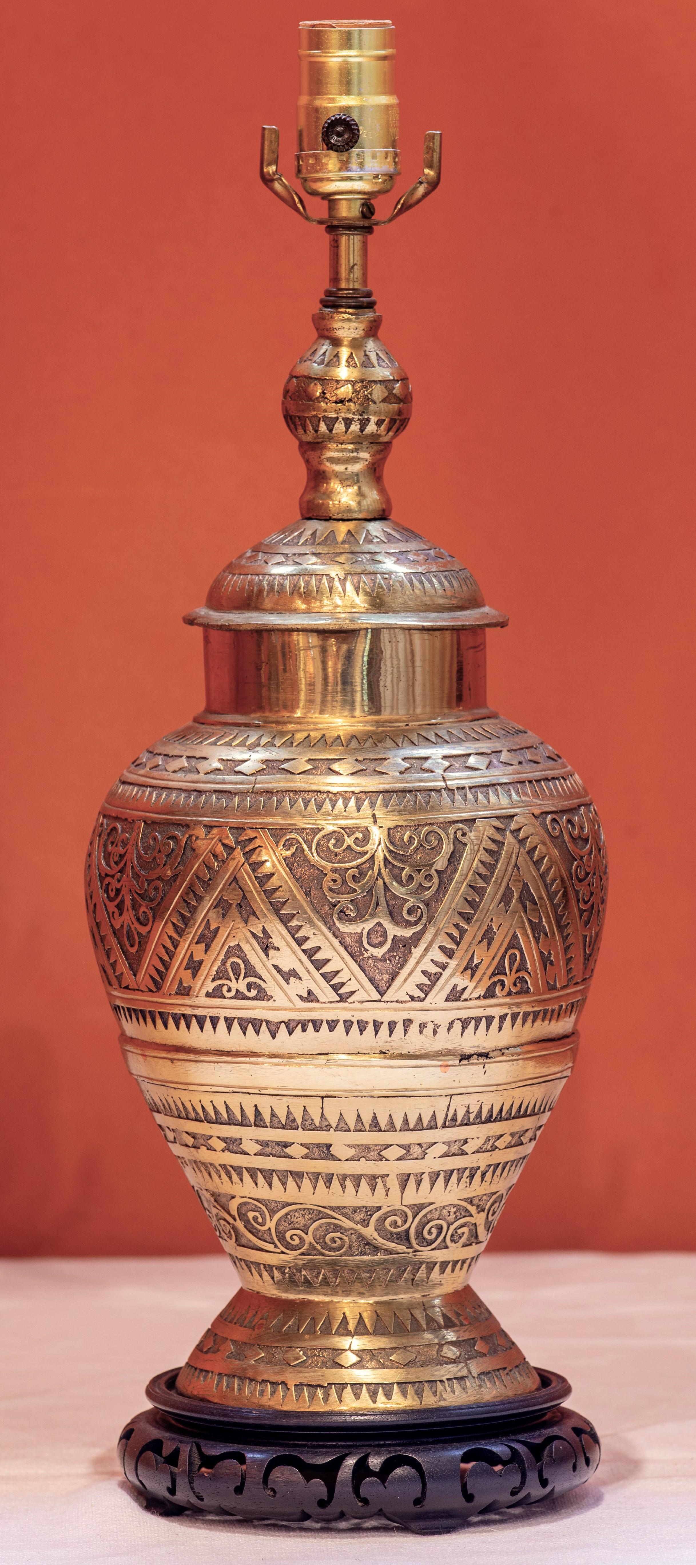 This lamp is of such nice quality.  It weighs over six pounds and its carving is intricate and beautiful  The lamp rests and a wooden base. The patina is original  We believe it to be from India. Some think that it is from Morocco.  It  has some
