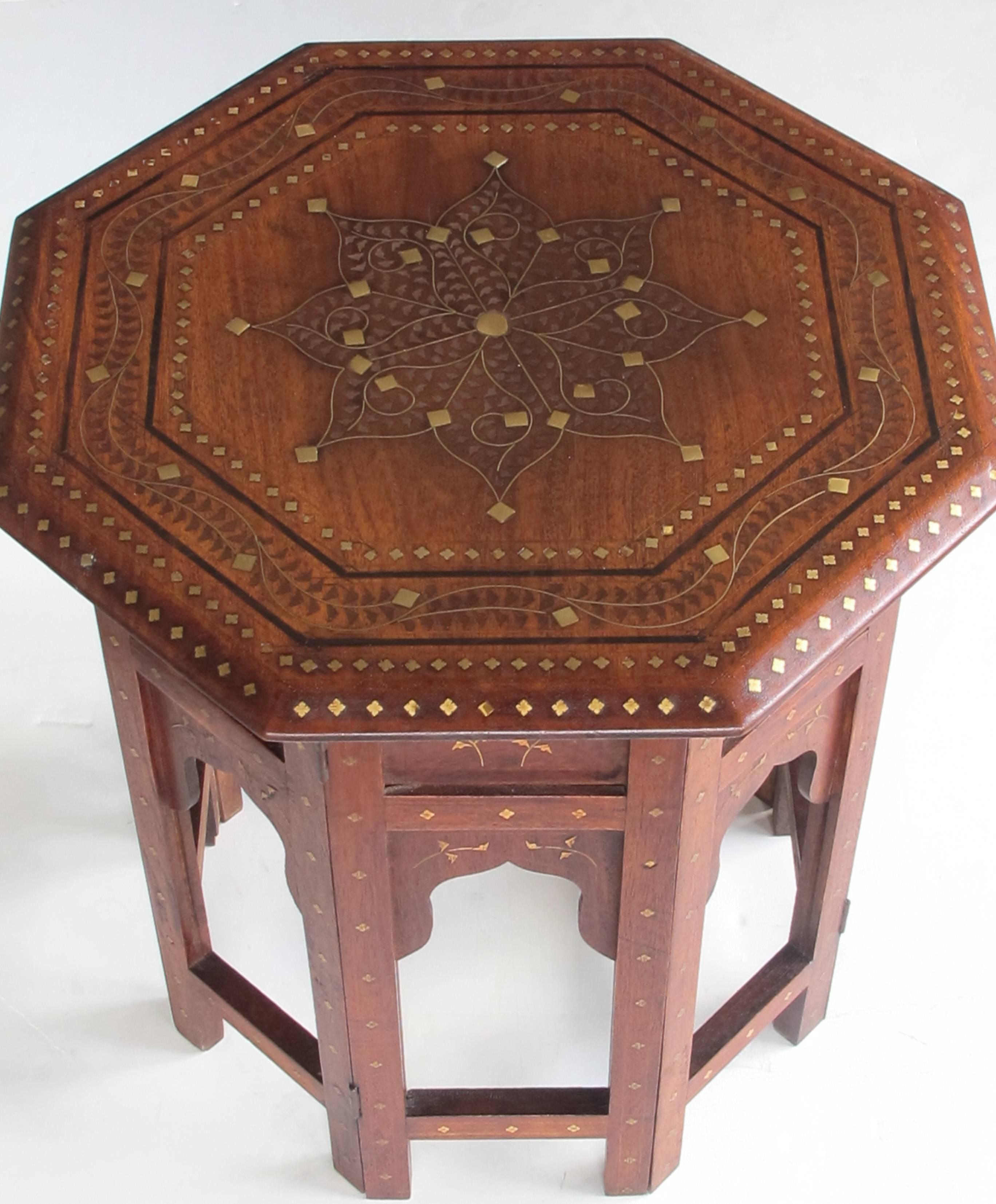 A very versatile and useful side table with octagonal top centring an intricately brass and pewter inlaid stylized star medallion within a meandering floral vine border; raised on an arabesque base with similar inlay.