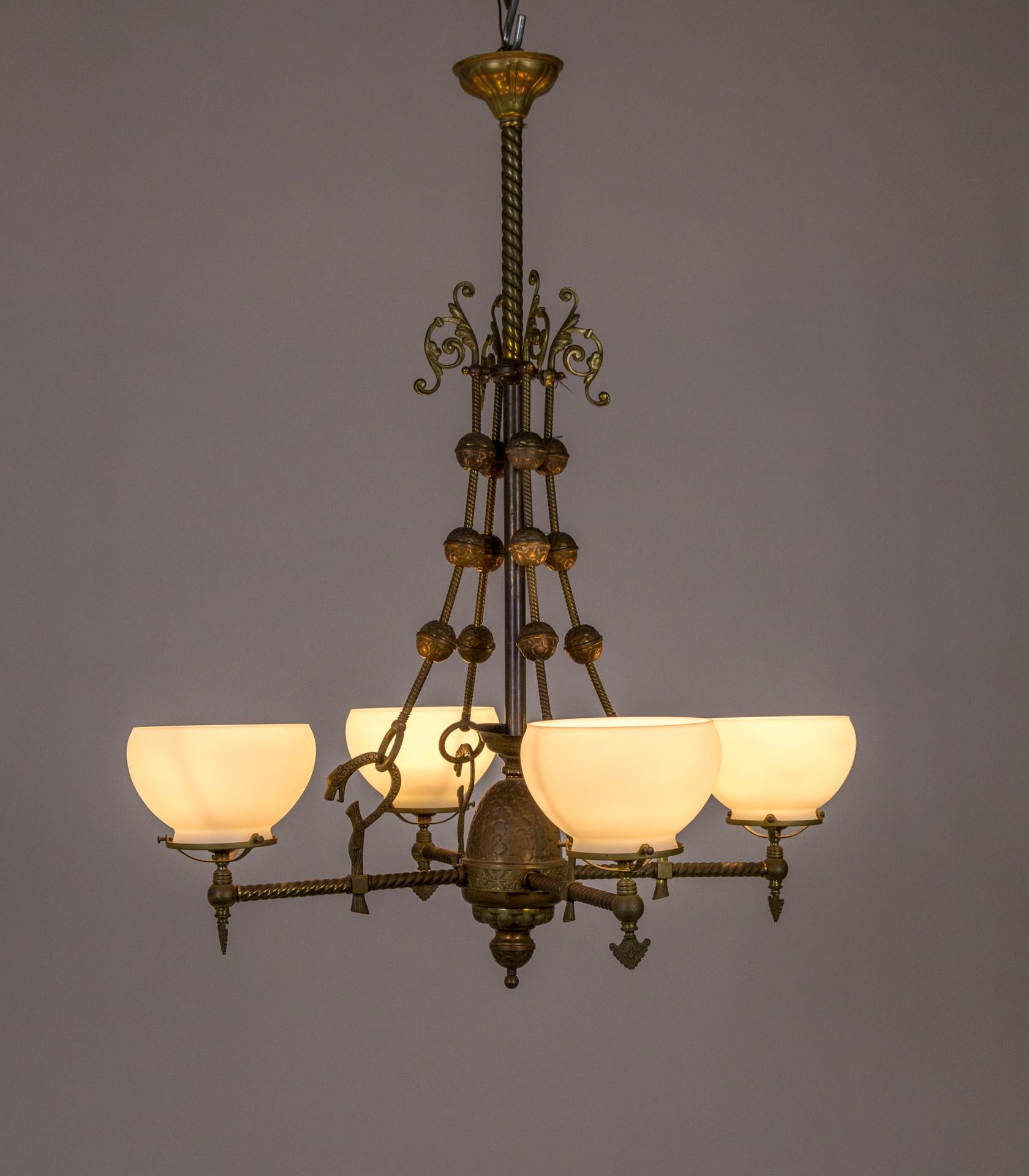 This quality, detailed chandelier takes a moment to fully appreciate. The main construction is of brass, with the detailing in embossed copper and brass. Notice the stylized cast bronze dragons atop tree trunks at the center
of each arm, and the