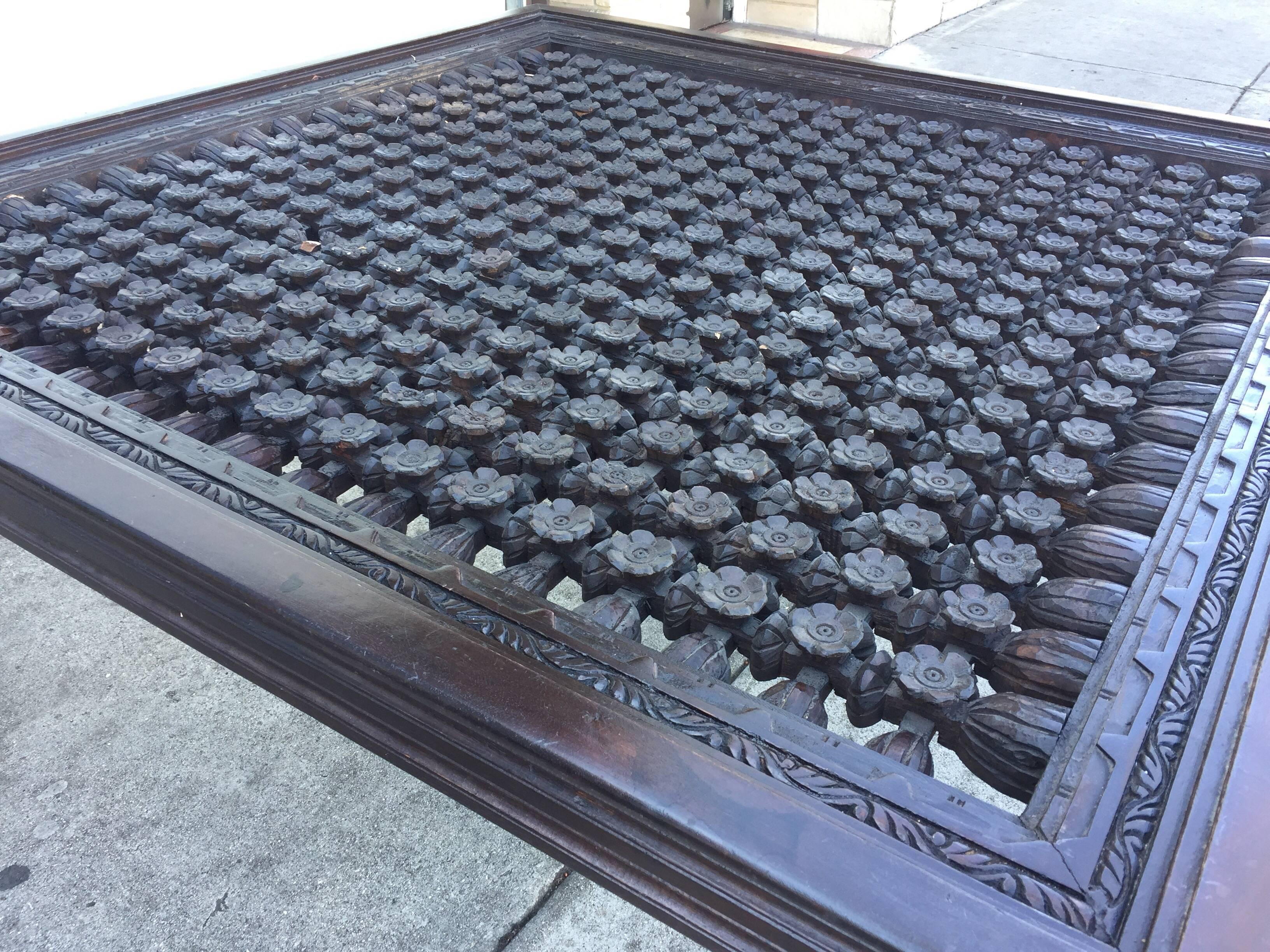 Intricately hand-carved Anglo-Indian style square dining table.
This custom wooden table is decorated with hundred of small hand-carved flowers.
Made using a window screen, or architectural panel.
Comfortably seats eight. You just need to add a