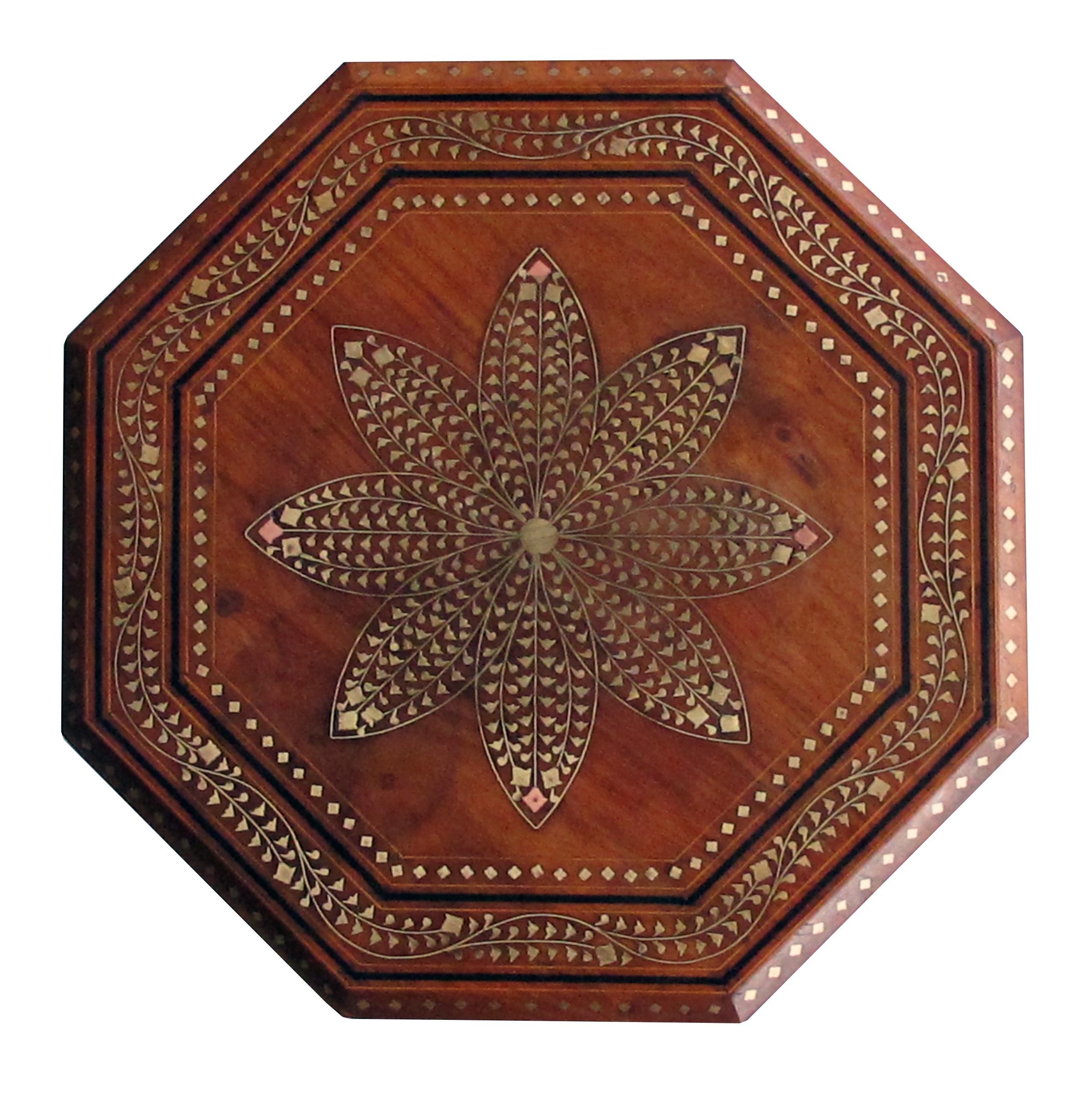 Originally used as travelling tea tables for the British in India; the octagonal top with central flower medallion surrounded by meandering foliate vines; raised on hinged openwork base.