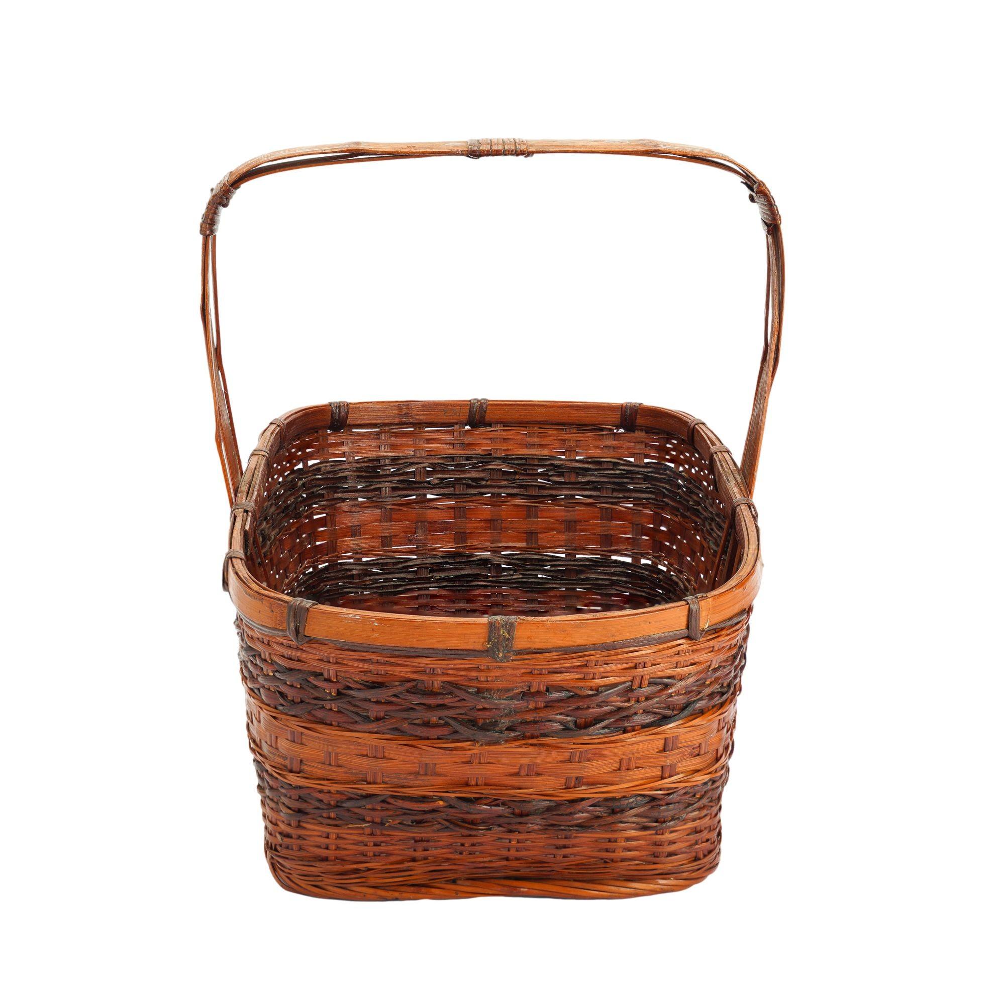 Vintage Japanese open top woven basket. The basket features a broad bent bamboo handle which is reinforced by angled bamboo stays lashed to the handle at both the bend in the handle and in the center of the handle's flat apex. The rim consists of