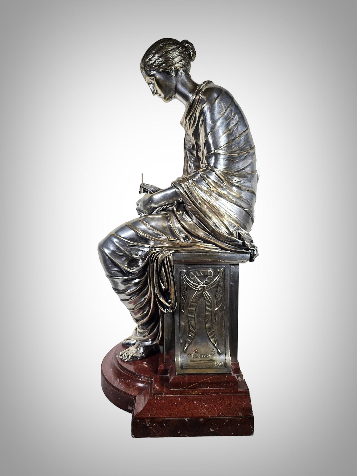 Behold this magnificent bronze sculpture depicting a possibly Greek lady seated, delicately holding a pencil. Crafted with exquisite detail, the sculpture boasts a silver finish that adds to its allure. What sets this piece apart is not only its