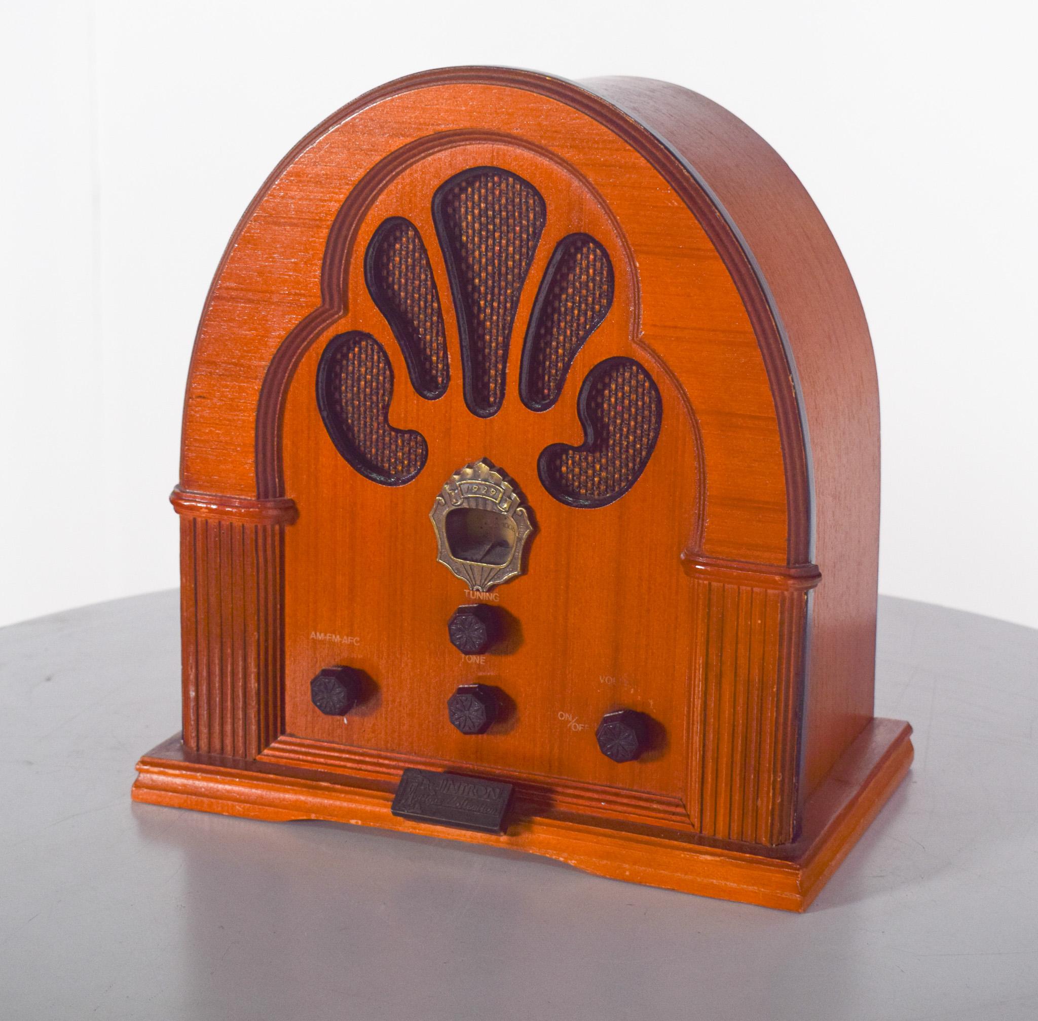 Radio de table Intron, Collectional.  Avec un cadre en bois plaqué et laqué, elle présente un design déco emblématique en forme d'arche, caractéristique des radios de l'époque. La face avant comporte une grille décorative en forme d'éventail qui