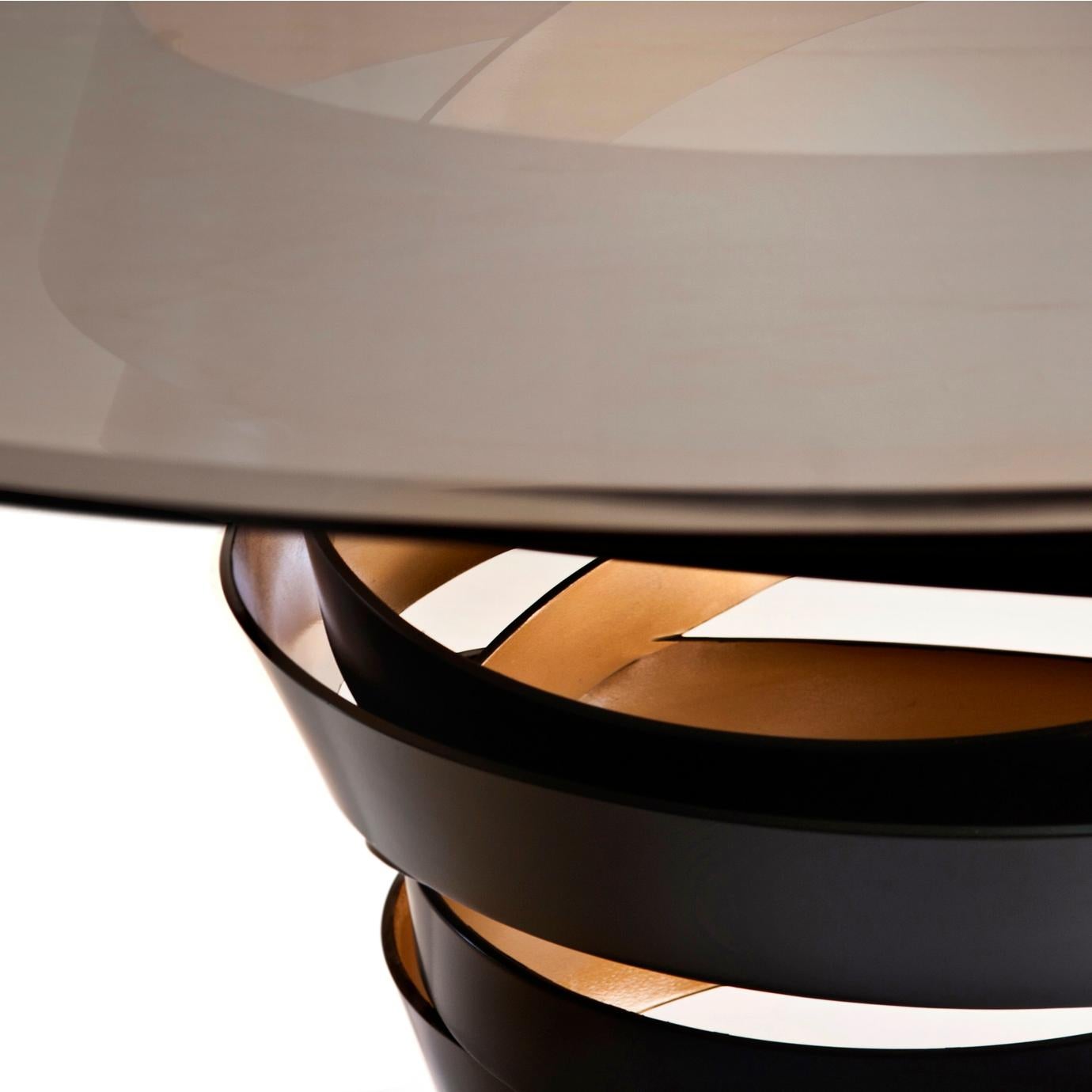 The swirling metal ribbon of the Intuition dining table evokes the mysterious and divine feminine instinct. Carefree and unexpected swirls are guided by emotions and desires. The two-tone metal base is topped with a perfect glass circle top. Without