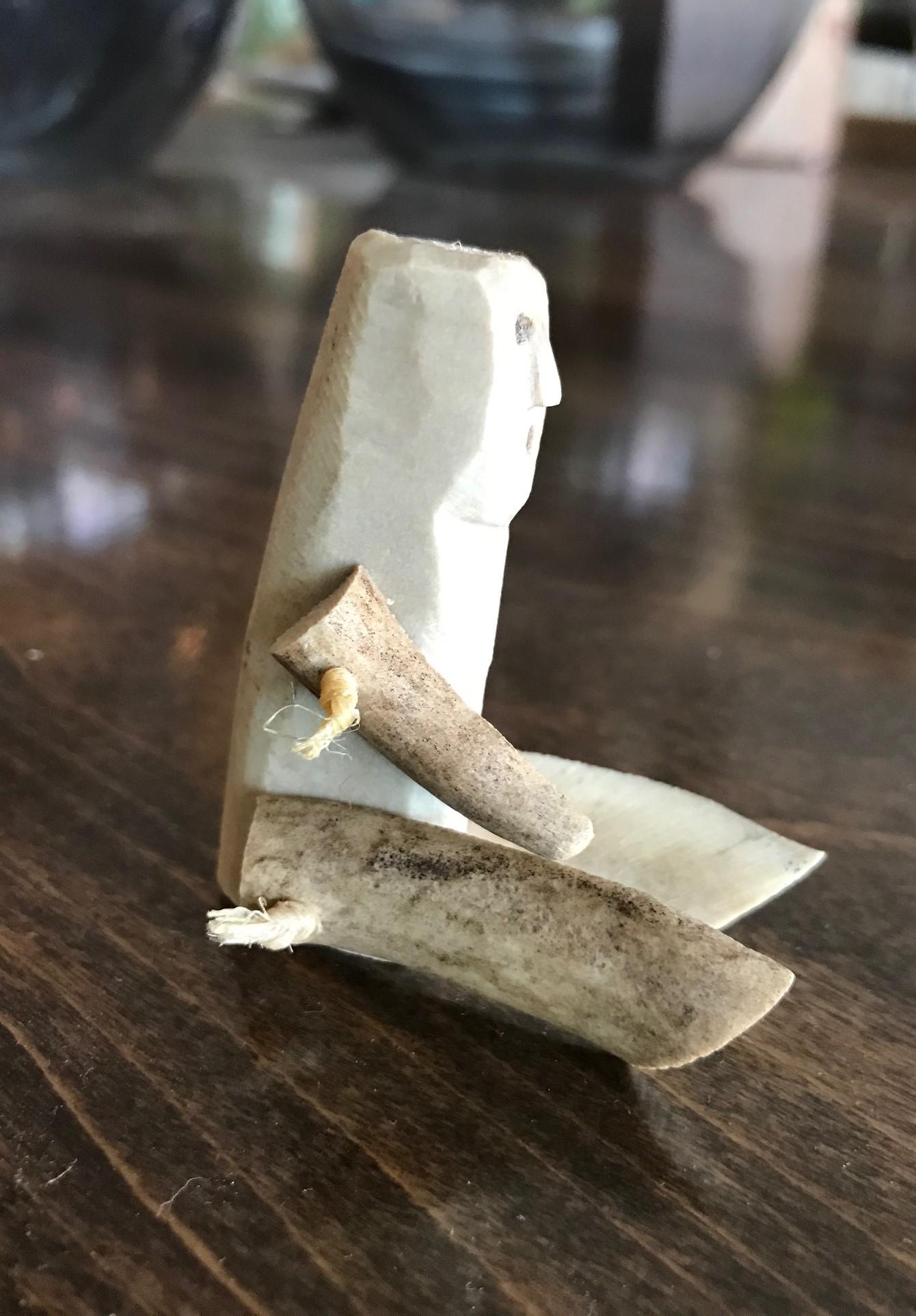 A curious, little hand carved from bone (likely caribou and/or antler) Inuit toy doll with movable hands and legs. These were often kept as tokens for good luck. 

Very similar examples can be seen in the Children's Museum in London and the