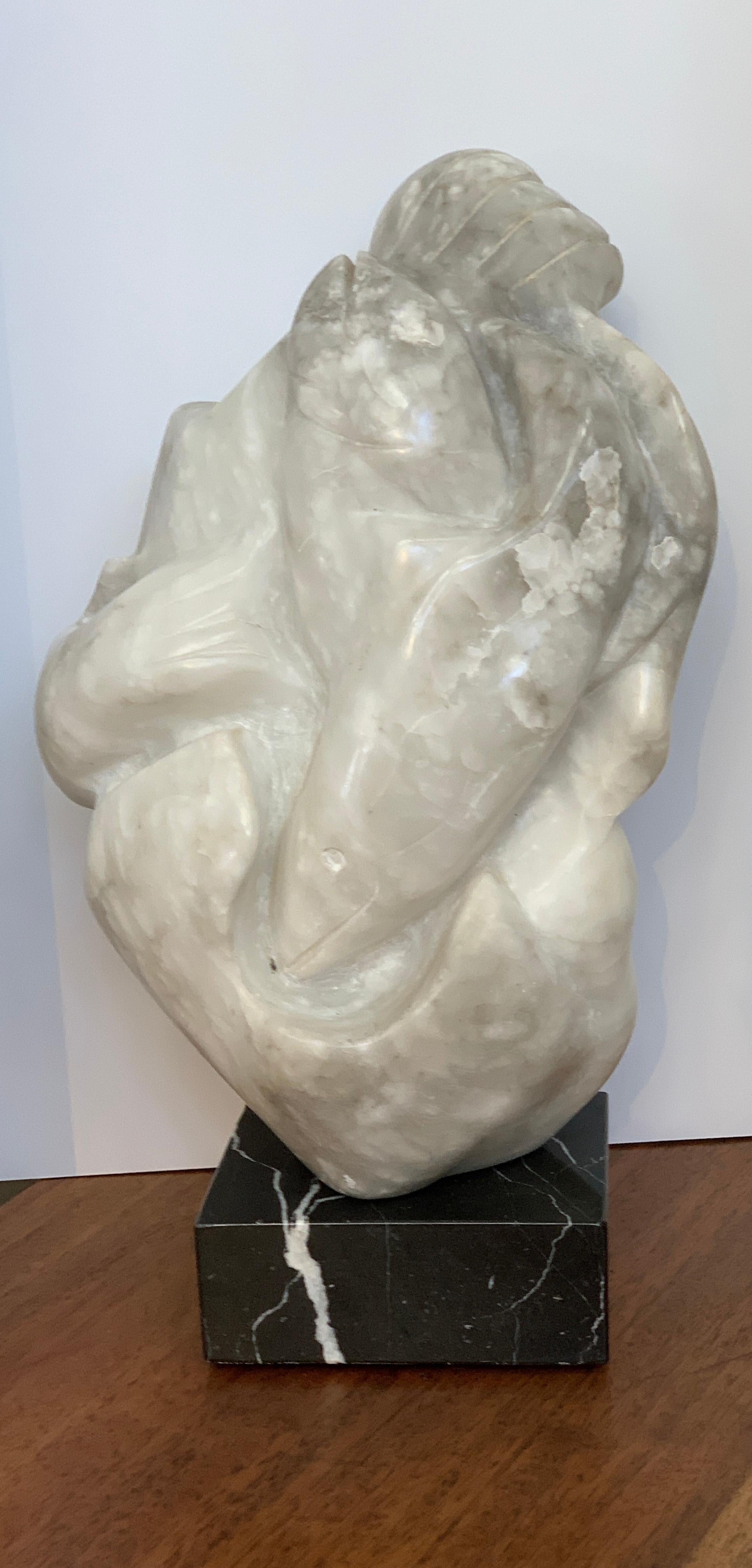 Una bella scultura in pietra di marmo con salmoni intrecciati, probabilmente di un artista Inuit. È montato su un'asta e su una base di marmo nero in modo da essere girevole. Un angolo della parte inferiore della base in marmo nero aveva una