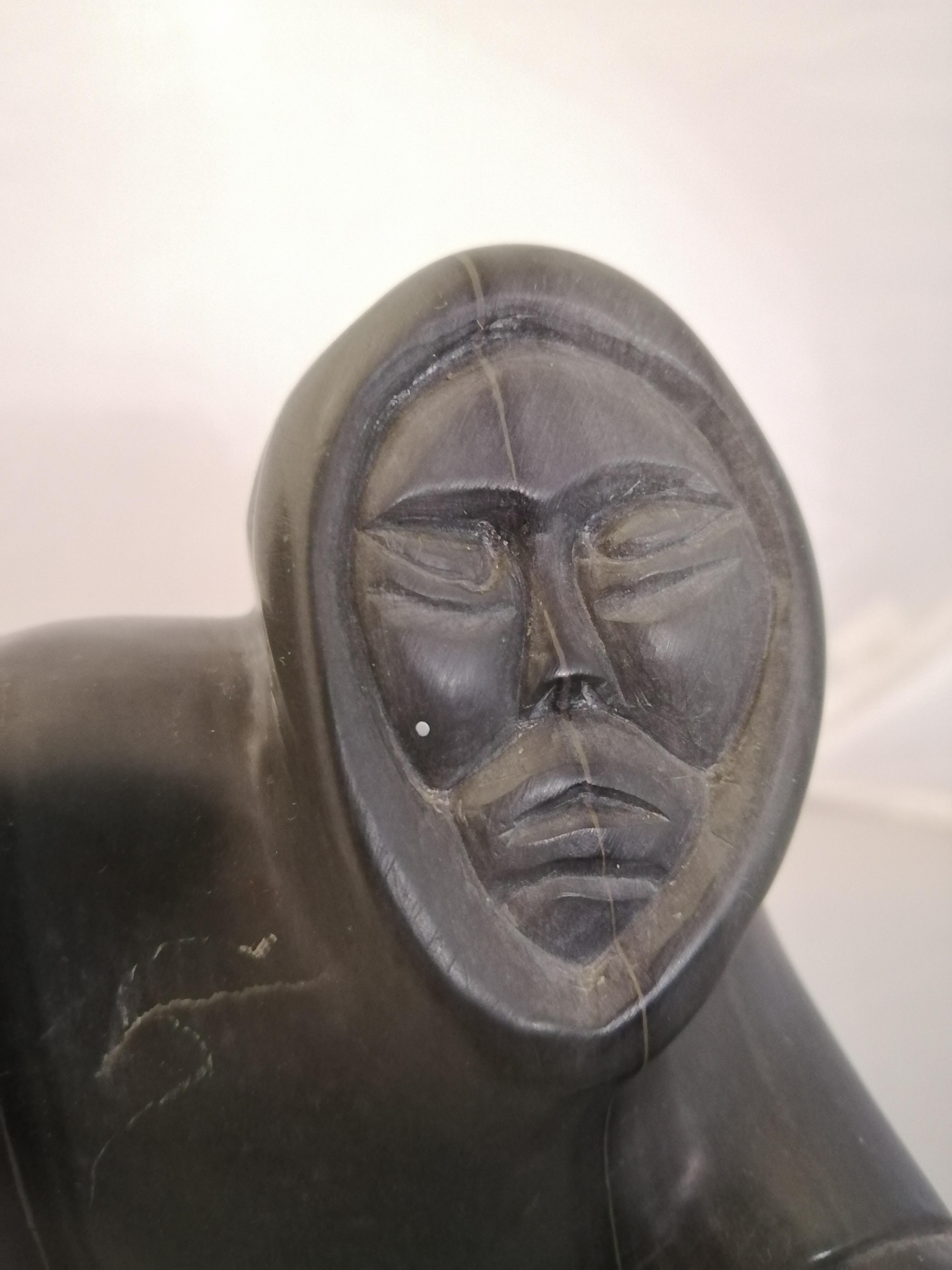 A Inuit carved dark green soapstone seal hunter. The sculpture is signed on the bottom by an unidentified artist. 

The sculpture doesn't have the hand's weapon, possibly a spear.
