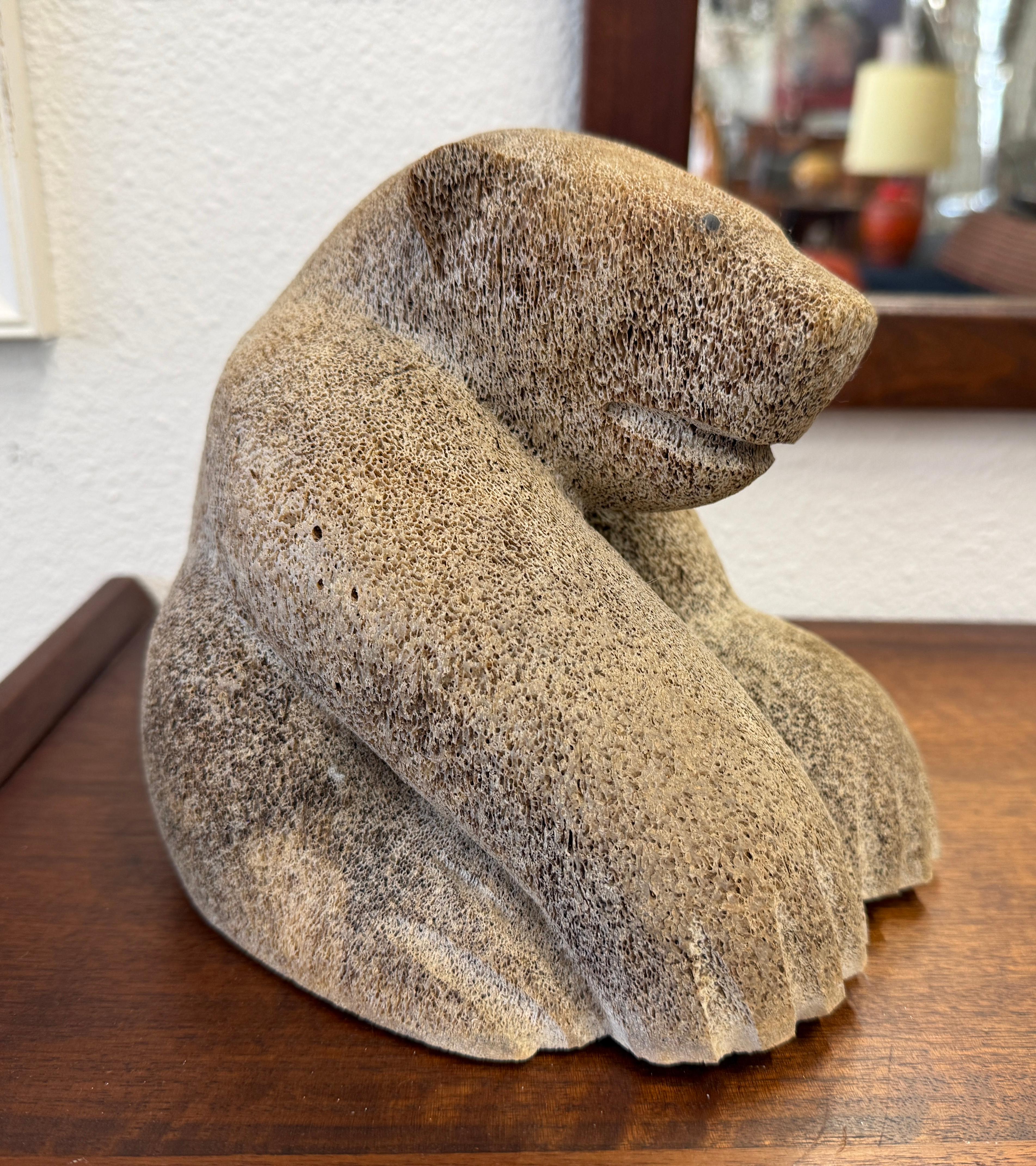 A wonderful and whimsical polar bear carving by the noted Alaskan intuit carver Wilson Oozeva (1953-2013). The fossilized bone carving lileky dates to the late 1970’s perhaps early 1980’s. The artist is pictured in a photo with the carving looking
