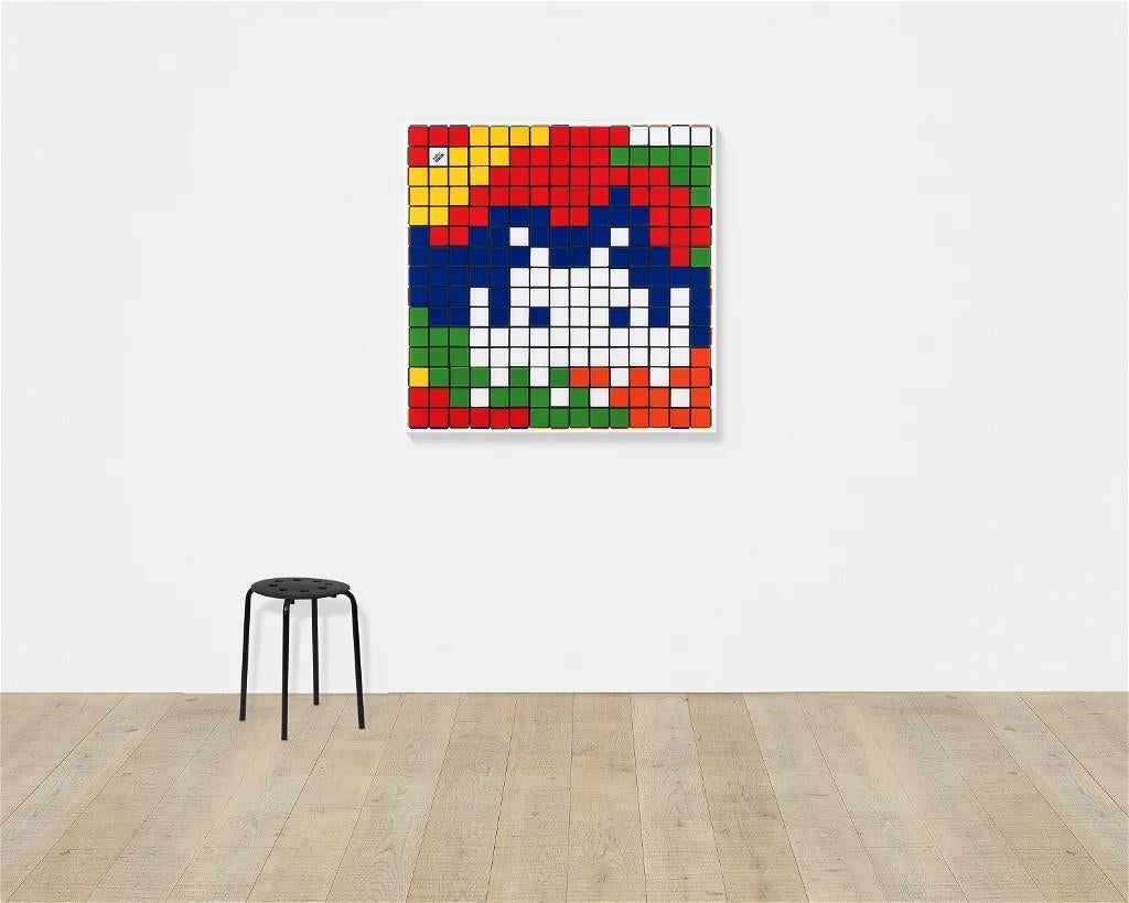 Der Druck Rubik Camouflage von Invader ist sinnbildlich für die Karriere des Künstlers als urbaner Disruptor. Seit Jahrzehnten überfällt er Städte auf der ganzen Welt mit seinen verpixelten Mosaiken, die oft von kultigen Videospielen aus der