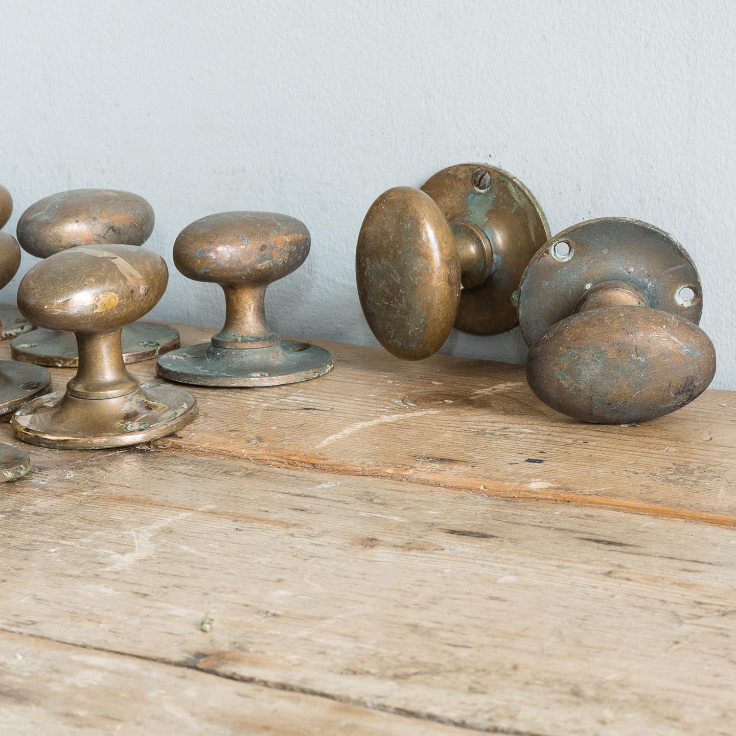 Antique patinated brass door handles, removed from Inverness Catering College, circa 1910-1920, the oval handles on circular backplates, with original unpolished patina.