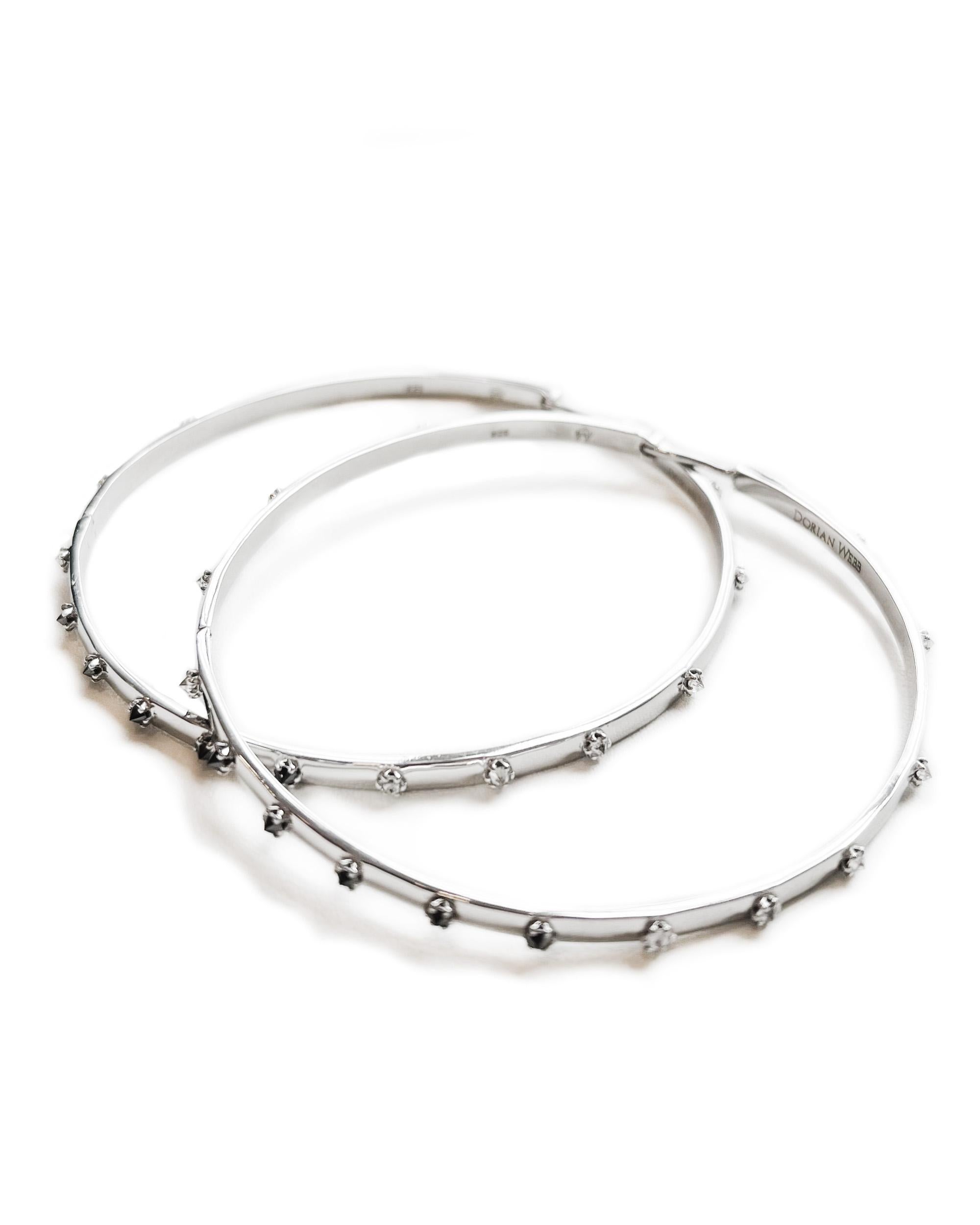 Intention: Savoring the Details

Design: An ombre' constellation of 2mm diamonds ranging from white to salt and pepper to black makes a welcome and subtle appearance in these streamlined hoops. Inverted in sterling silver settings, the usually