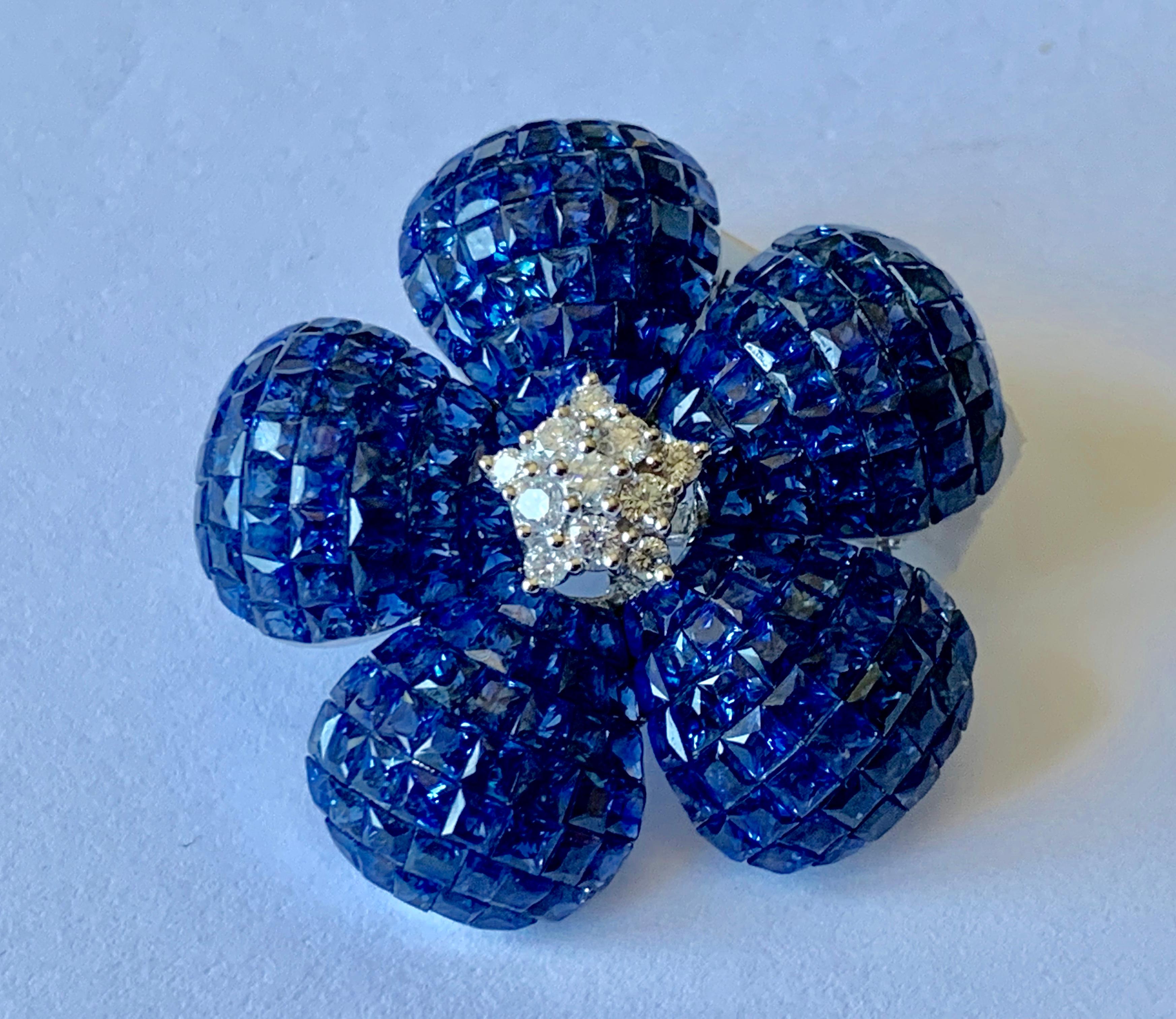 This outstanding flower brooch and pendant is handcrafted in solid 18K white gold weighing approx. 18.18 grams. It features a floral design of bombé calibrated 220 royal blue genuine sapphires petals (in invisible mystery setting which was