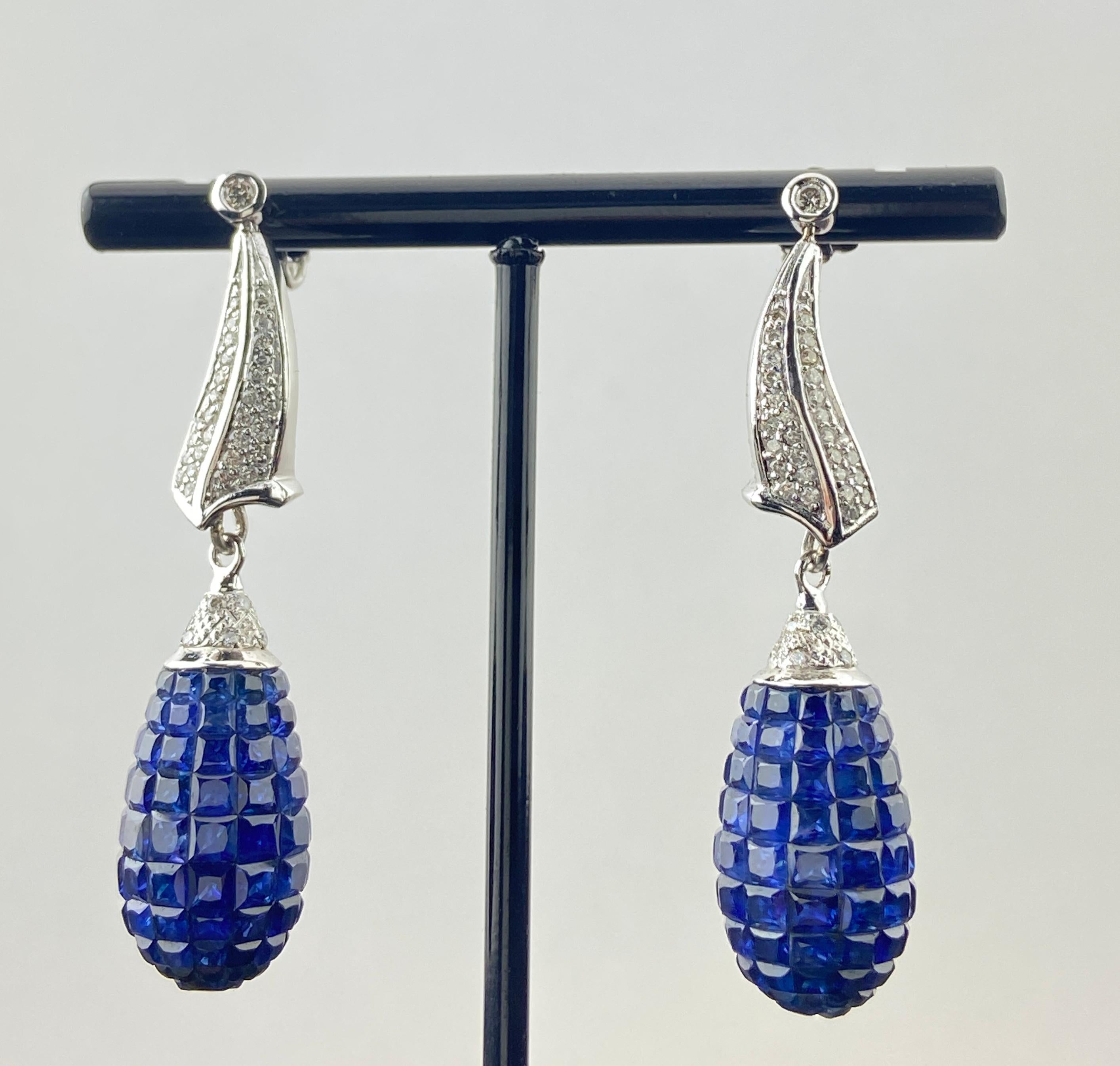 Diese bezaubernden Ohrringe sind eine Meisterklasse in raffinierter Eleganz und skulpturalem Design. Mit 28,51 Karat unsichtbar gefassten blauen Saphiren strahlen die birnenförmigen Tropfen in einem tiefen, samtigen Farbton. Oben zeichnen 1,50 Karat