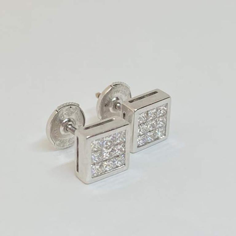 Beautiful square shape post stud earrings designed in 18 karat white gold. The earrings contain eighteen square princess cut faceted diamonds, three in each row. The diamonds are tongue and groove invisibly set in a square bezel setting. Post and la
