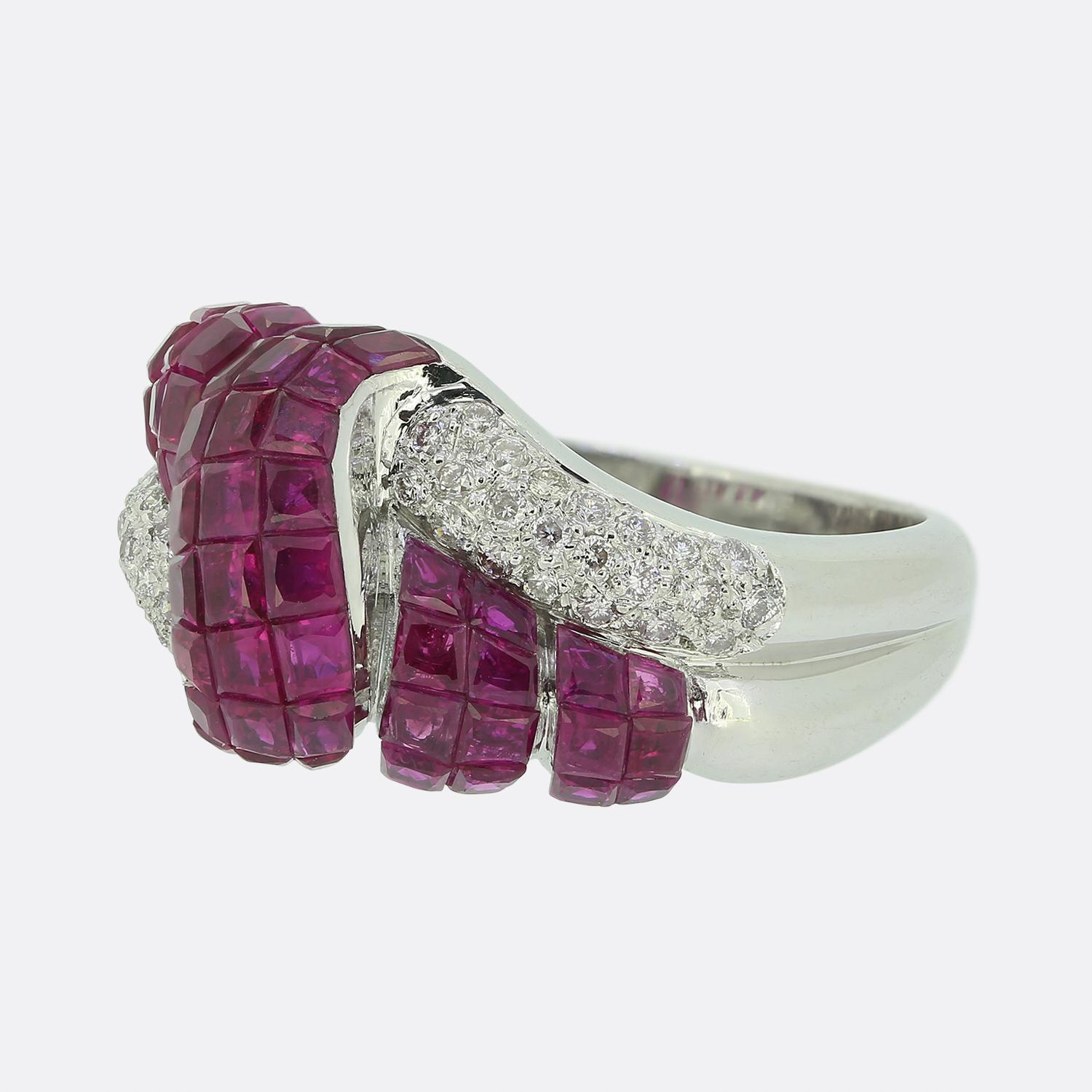 Here we have a striking ruby and diamond ring. The design features vibrant red rubies with a slight pink undertone meticulously set in an swirling intricate pattern. Interwoven with the rubies are pavé set brilliant-cut white diamonds, adding a