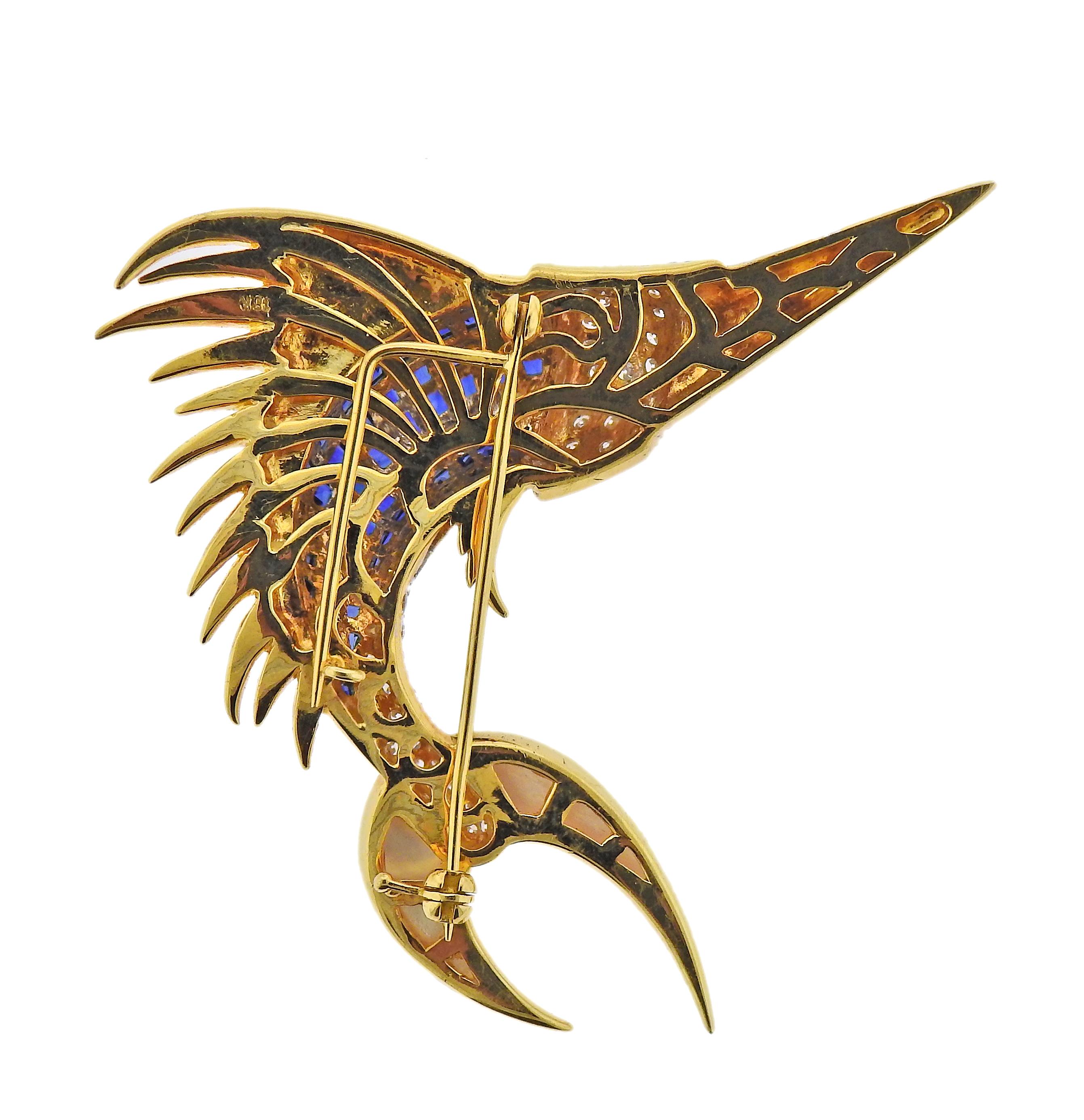 18k gold fish brooch, featuring invisible set blue sapphires, carved mother of pearl, ruby eye and diamonds. Brooch is 65mm x 67mm. Marked 18k. Weight - 30.3 grams. One small sapphire is missing. 