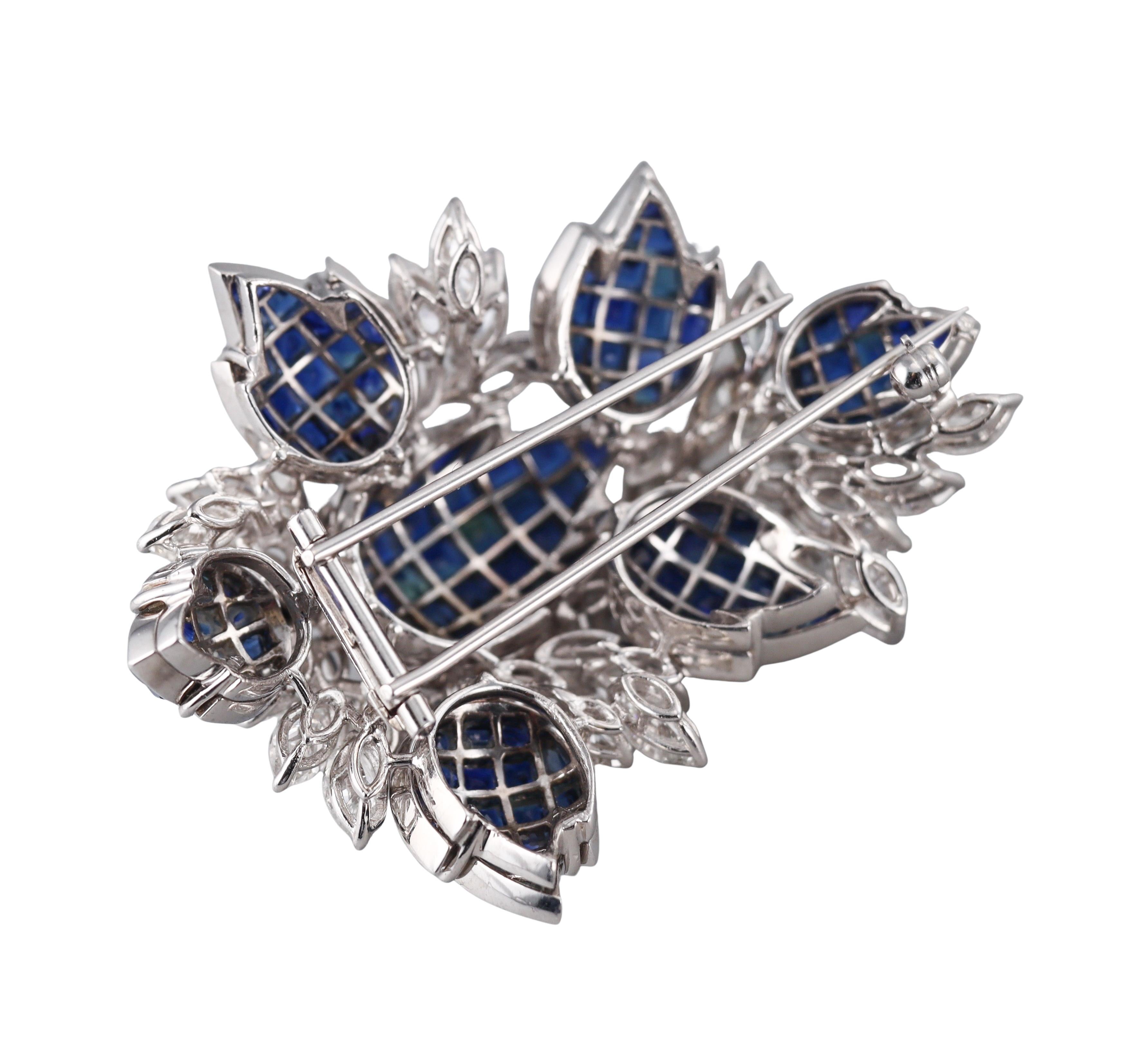 An 18k white gold brooch, set with vibrant invisible set sapphires and approx. 10ctw in GH/VS diamonds. Brooch measures 2