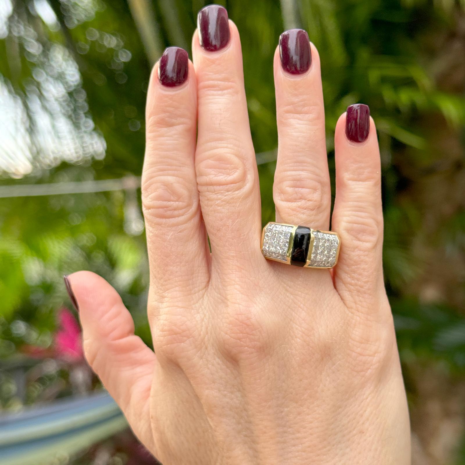 Contemporary invisibly set diamond and onyx ring handcrafted in 18 karat yellow gold. The ring features 40 princess cut diamonds weighing approximately 2.00 carat total weight and graded G-H color and SI1 clarity. The center is set with a cabochon