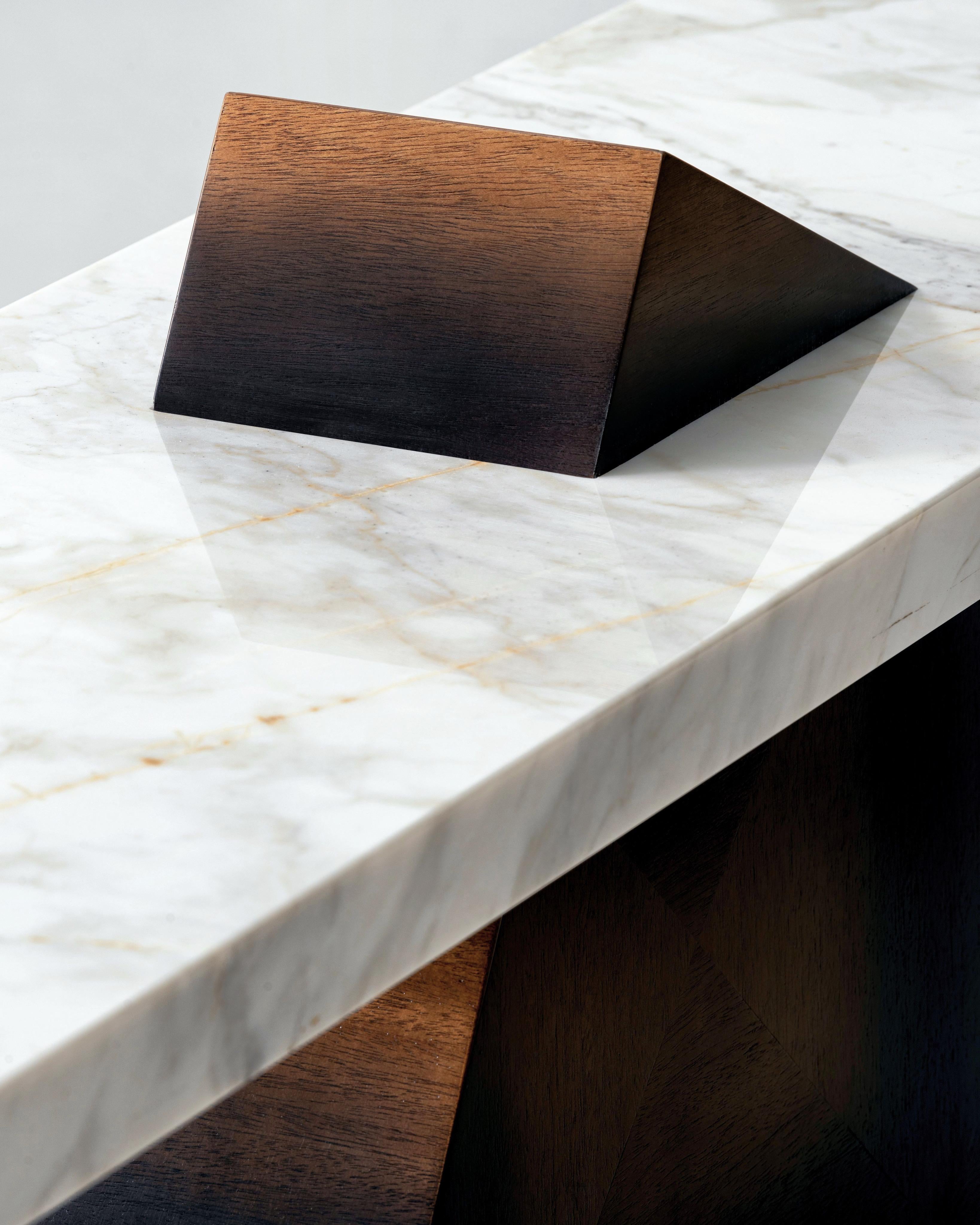 A symphony of form and function, the tilted balance of the console table beckons with its striking deconstructionist design. Calacatta gold marble and richly stained walnut wood come together in a subtle gradient, inviting one to surrender to
