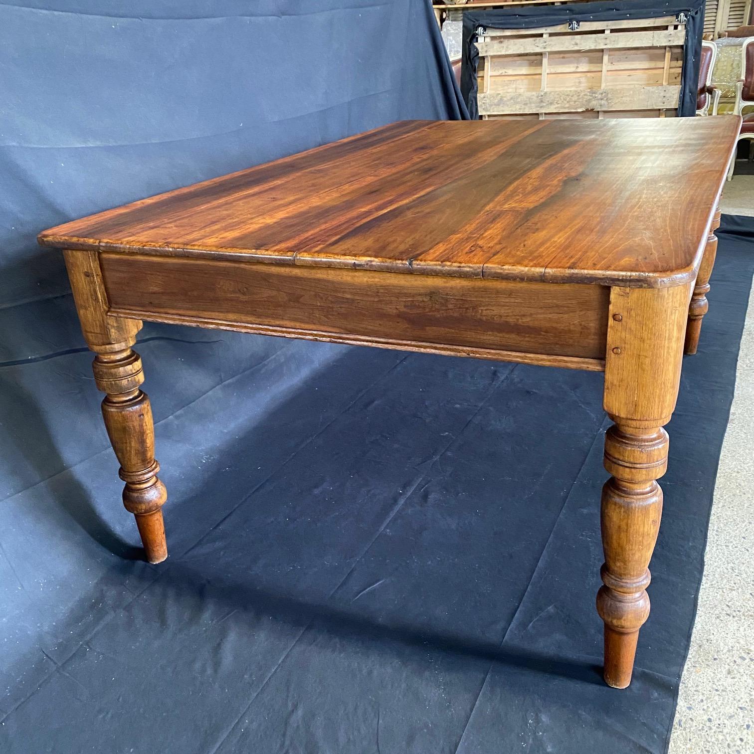 British country pine farmhouse dining table having a character rich plank wood top with tongue in groove joinery and solid round turned legs that give the table a very solid substantial feel.  Excellent joinery and craftsmanship with a lovely aged