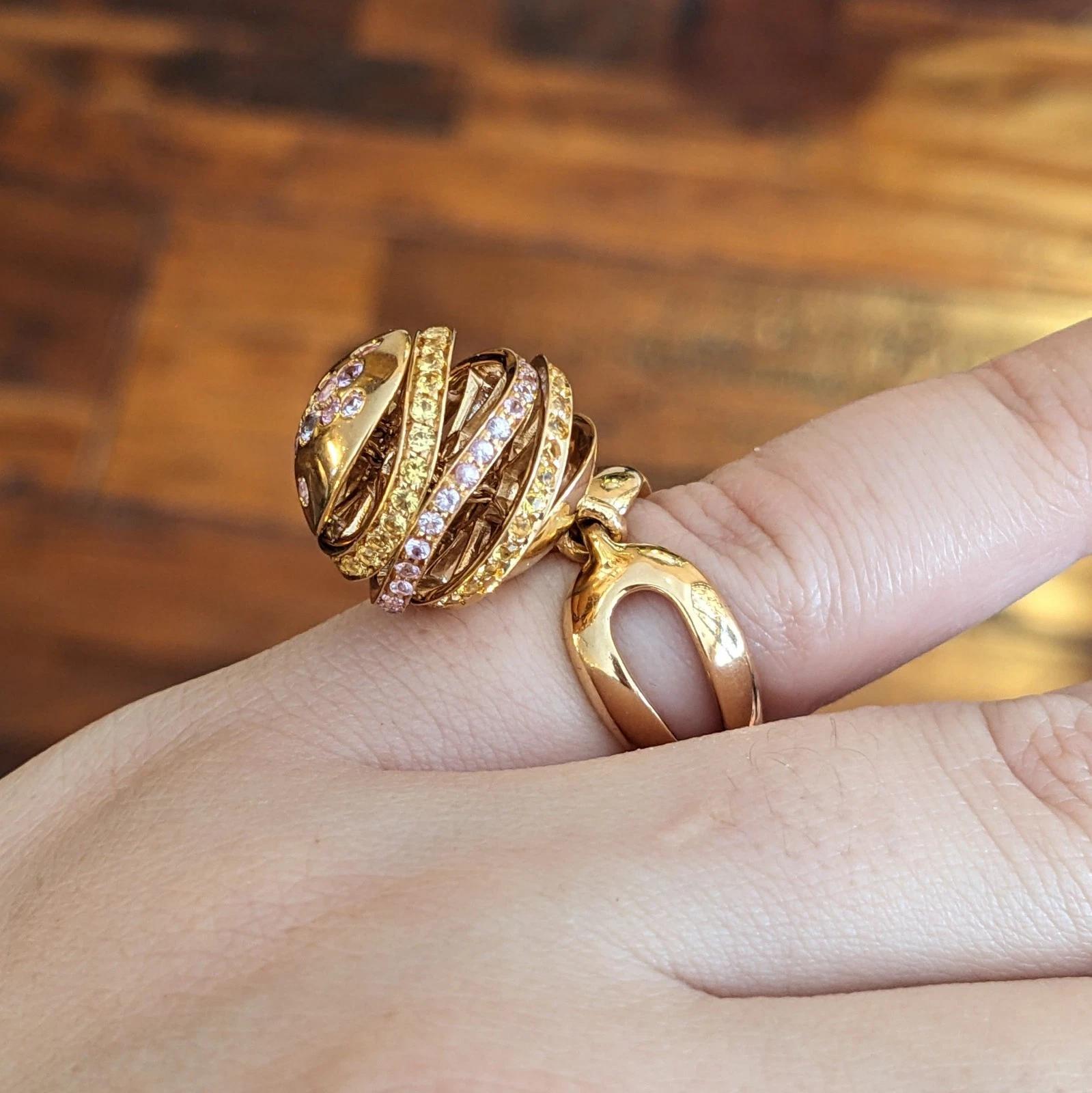 iO Si Italien Rosa und gelber Saphir Kugel Ring in 18k Rose Gold

Einzigartiger Bauble Ring von iO Si mit rosa und gelben Natursaphiren in Bändern und einer baumelnden, beweglichen Kugel, eingefasst in einen herzförmigen Schaft aus 18 Karat