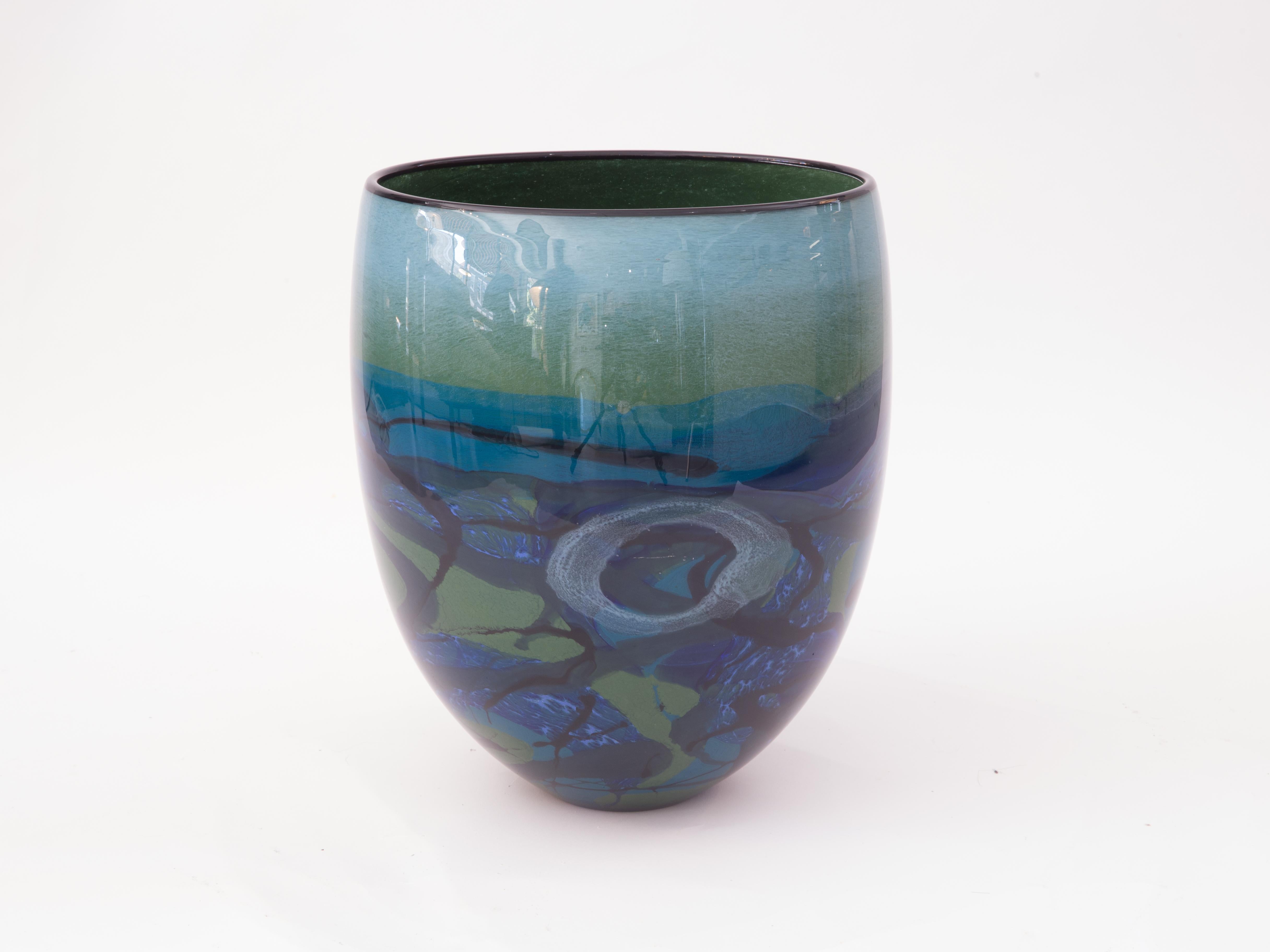 This vase is a vibrant green and blue work that was created by Ioan Nemtoi. The Artist-signed the vase. The vase has a black rim, with various abstract designs. Born in Romania in 1964 he attended the Academy at Bucharest, his works are now selling