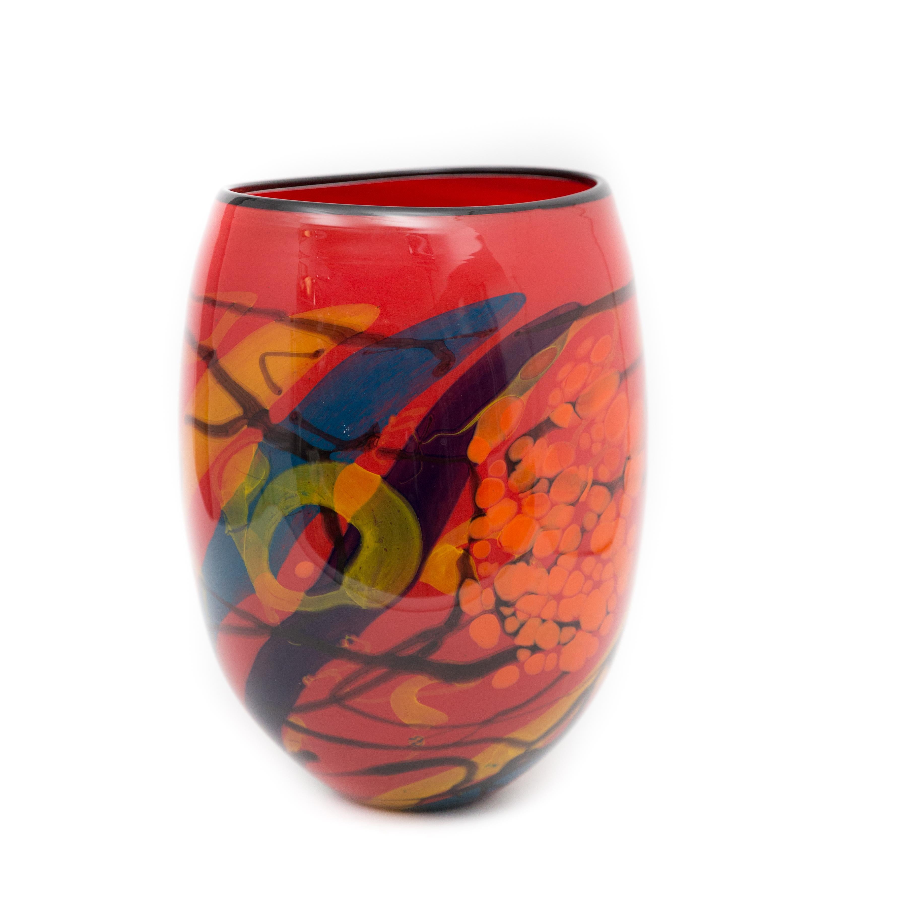 This vase is a vibrant red yellow and blue work that was created by Ioan Nemtoi. The artist signed the vase. The vase has a black rim, yellow and blue designs throughout, on a red ground. Born in Romania in 1964 he attended the Academy at Bucharest,
