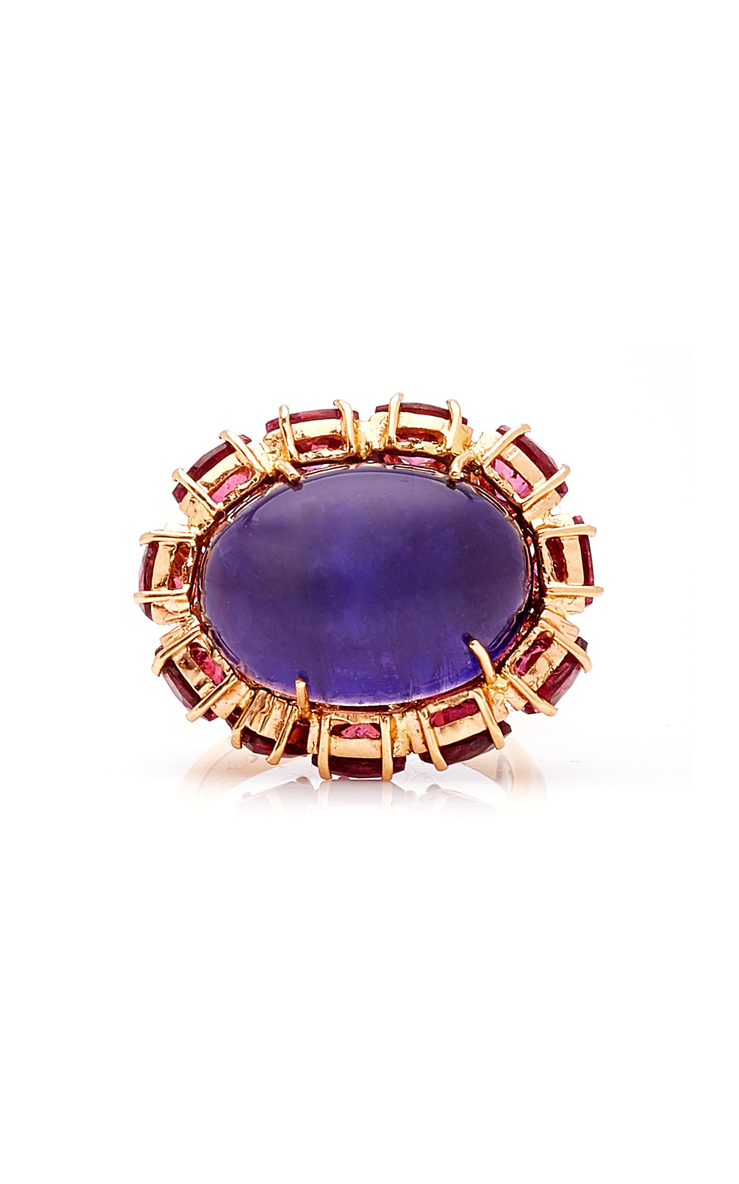 Violett-blaue und fuchsiafarbene Farbtöne .... Dieser bezaubernde Ring zeigt einen großen indigoblauen Iolith-Cabochon, der aus einem Bett aus glitzerndem magentafarbenem Rhodolith im Billionenschliff hervorragt.

18k Rose Gold, Iolith und