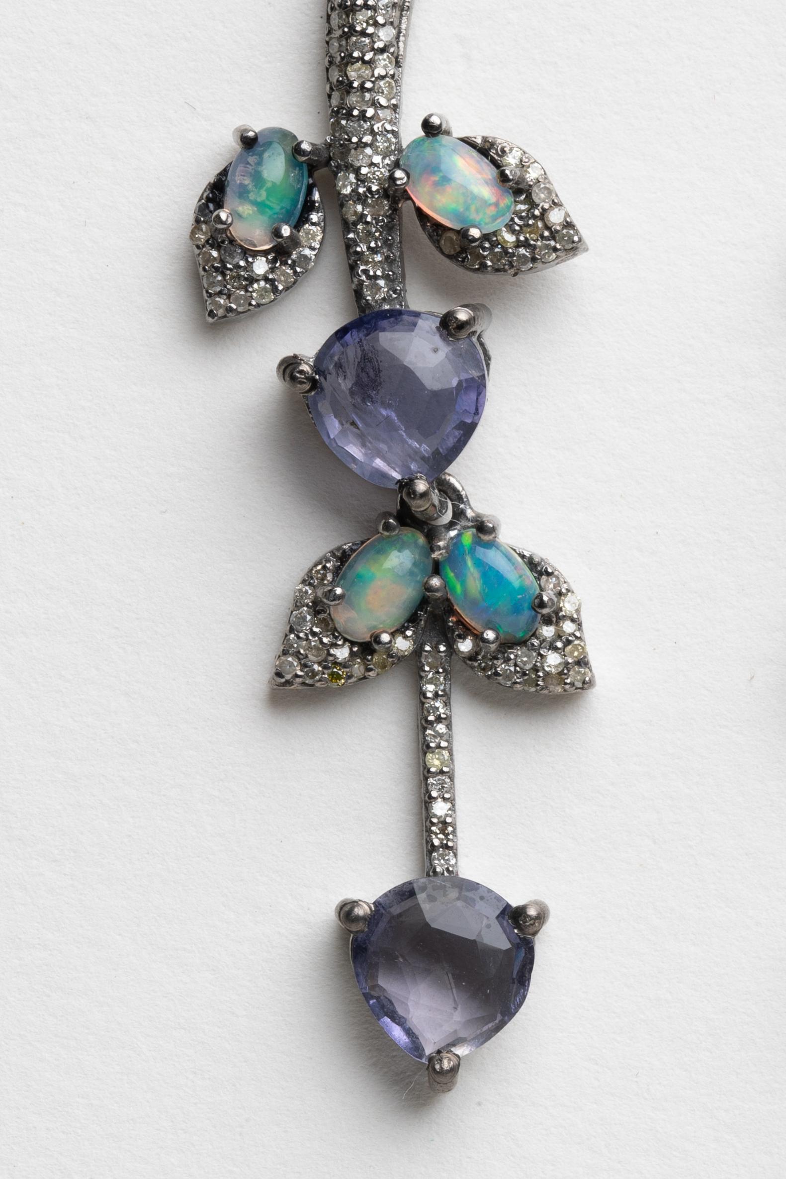 Unusual and striking, a pair of dangle earrings with a subtle leaf motif.  Round, faceted iolite stones as the blossoms with oval, fiery, opals as the leaves and pave`-set diamonds all along the stem and border to the leaves.  Iolites total 5.2