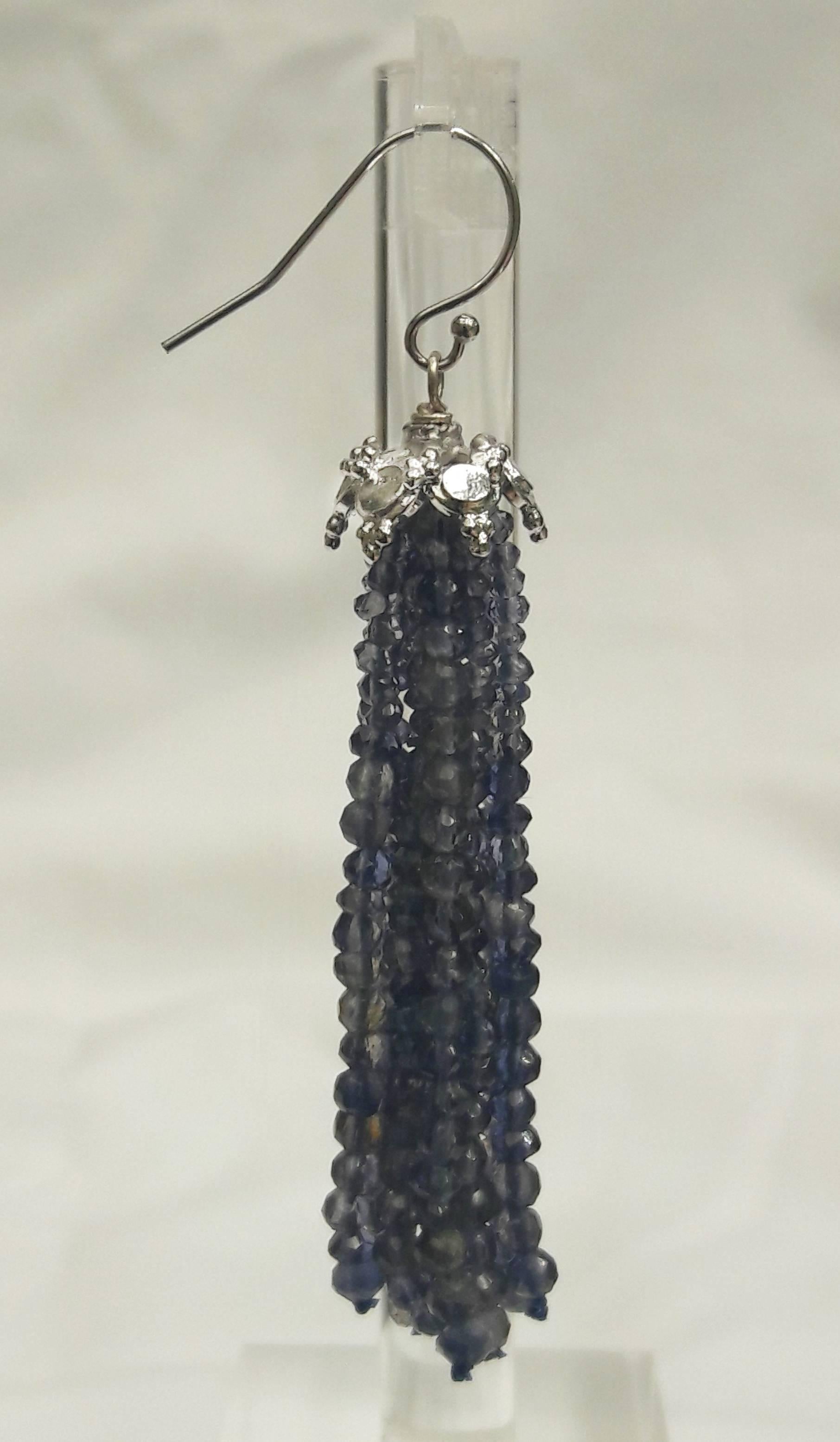 The many tones of blue faceted iolite beads have a translucent glow that is highlighted by the rhodium plated 14k white gold designed cup, and completed with a 14k white gold hook. These earrings are whimsical and beautifully play with light as the