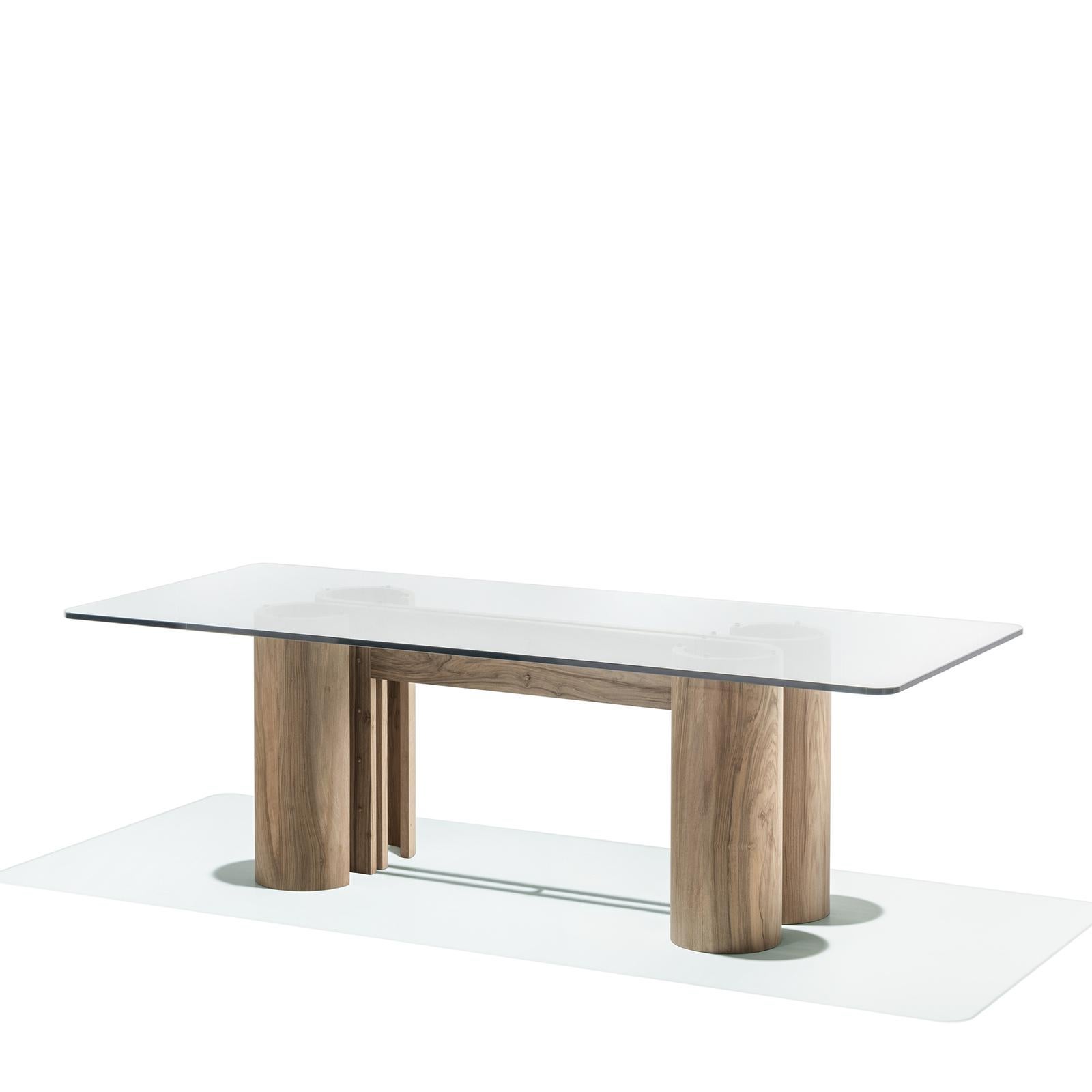 This modern table has a rectangular silhouette distinguished for its distinct architectural flair. The understated base is made of walnut and comprises four column legs with a polished finish connected at the centre by a double, U-shaped element.