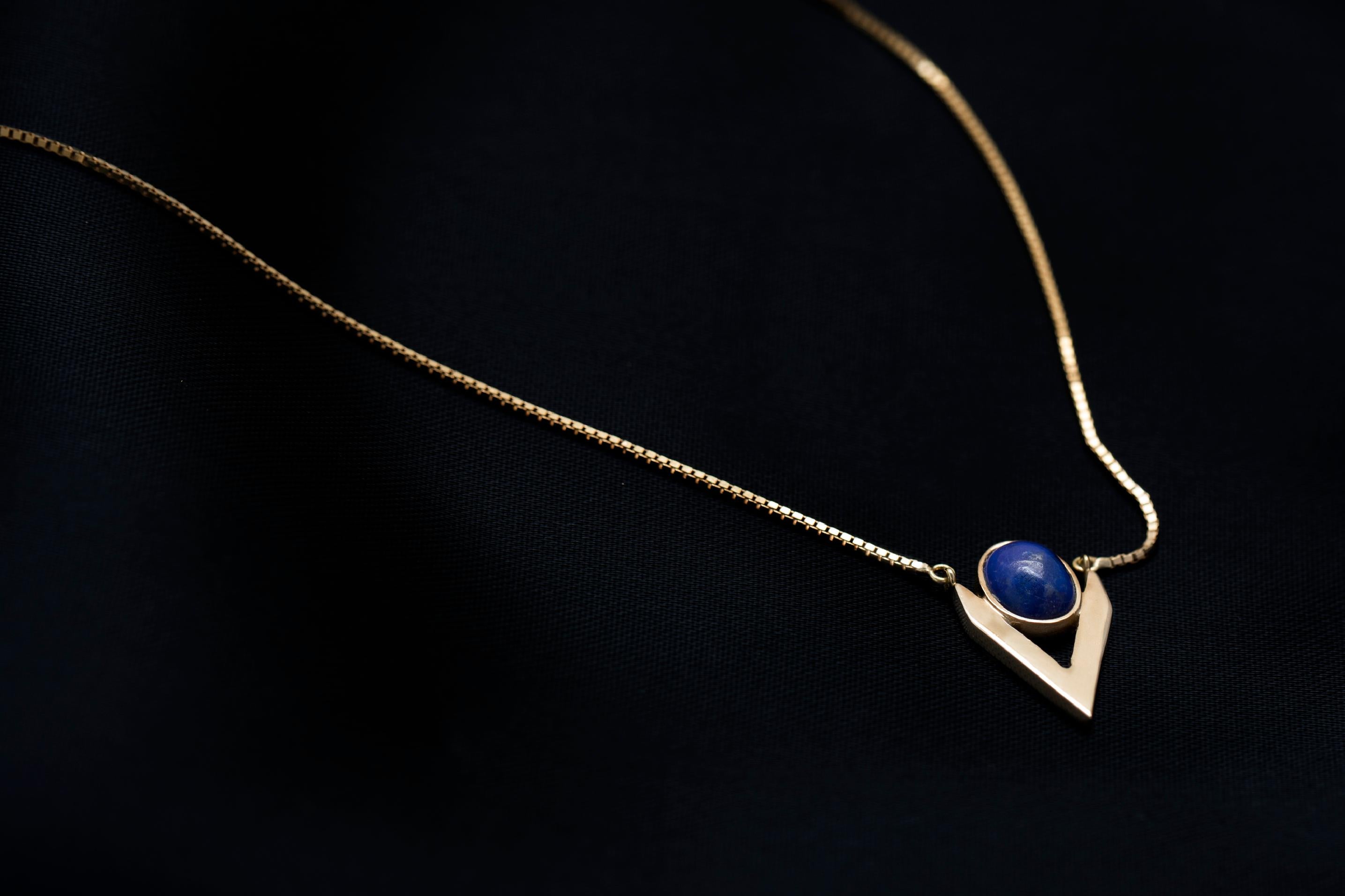 Iosselliani jewellery pieces are intended to be the new classic with an edgy style. Designed with a 9 Karat gold chain, the necklace features a lapis lazuli cabochon framed into a V shape. Bringing geometry to your look this piece will allow you to