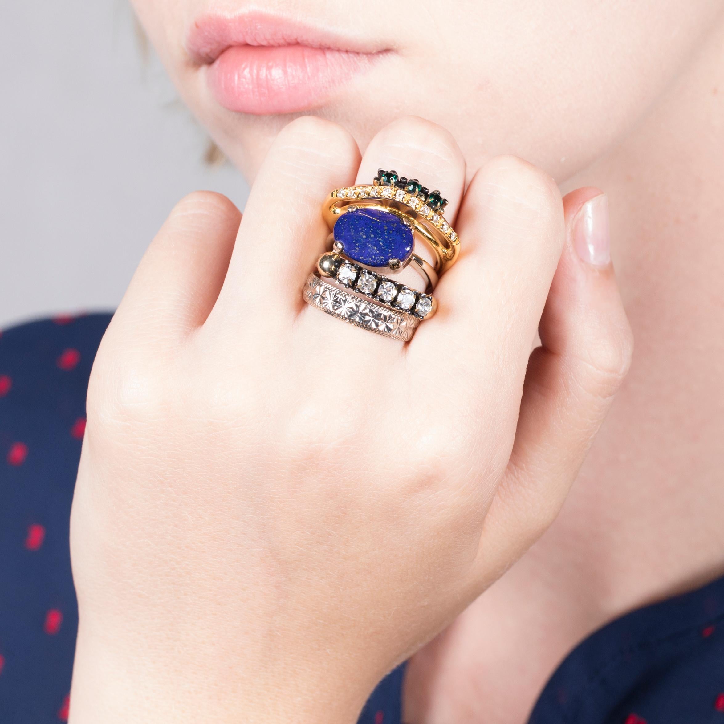 Enjoy Iosselliani’s love for mixing shapes and materials with this set of 5 mixed plating gold rings. This antique gold tone set of 5 rings is accented by a lapis lazuli oval stone casted into a delicate vintage set. Green and crystal zircons will