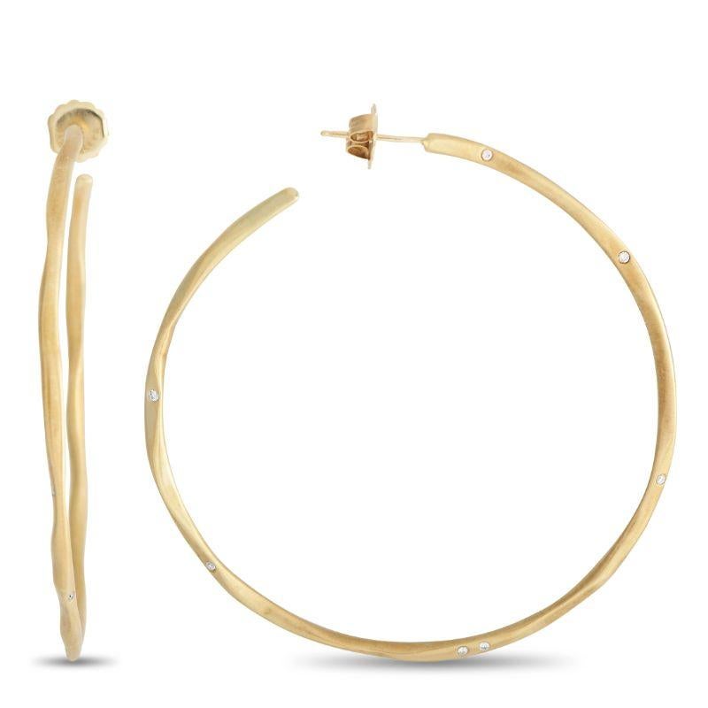 These hoops sure know how to make a subtle style statement. Each hoop is handmade from 18K yellow gold and infused with a delicate sparkle. Diamonds are set flush to the slender, organic-shaped hoop and are positioned in an irregular pattern for