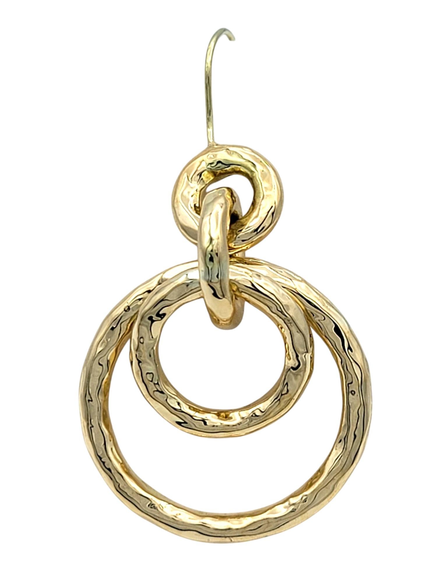 Elegia il tuo stile con questi orecchini a cerchio multipli in oro, un mix perfetto di eleganza moderna e artigianalità. Realizzati in oro giallo 18 carati dalla texture ricca, ogni orecchino presenta tre anelli intrecciati con finitura martellata