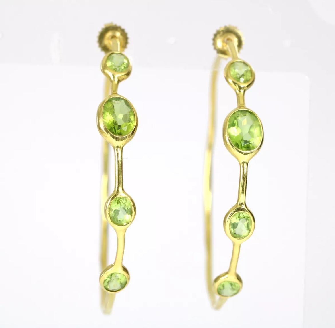 Add a pop of color to your outfit with these beautiful Ippolita hoop earrings. The large 2.25 inch diameter circle earrings feature four stunning green peridot stones with a total weight of approximately 12 carats in a bezel setting. The gold is
