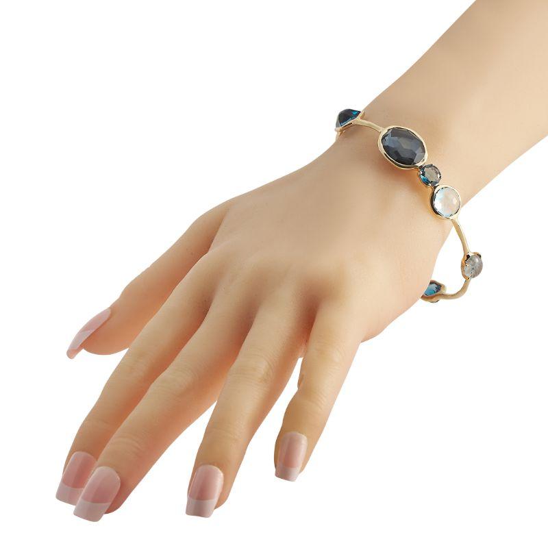 Cast from 18K yellow gold, this stunning bracelet that's carefully handcrafted would make a gorgeous addition to your jewelry collection. The bangle is mounted with multiple hand-cut faceted gemstones including onyx, Swiss blue topaz, clear quartz