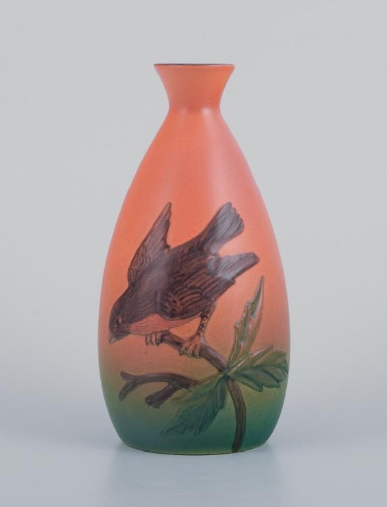 Ipsens, Denmark, ceramic vase with a bird motif on a branch. 
Glaze in green and orange tones.
Approximately 1930.
Model number: 432.
Marked.
In perfect condition.
Dimensions: H 16.5 cm x D 8.0 cm.