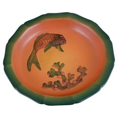 Ipsens, Dänemark, Schale mit Fisch und Glasur in orange-grünen Farbtönen. 