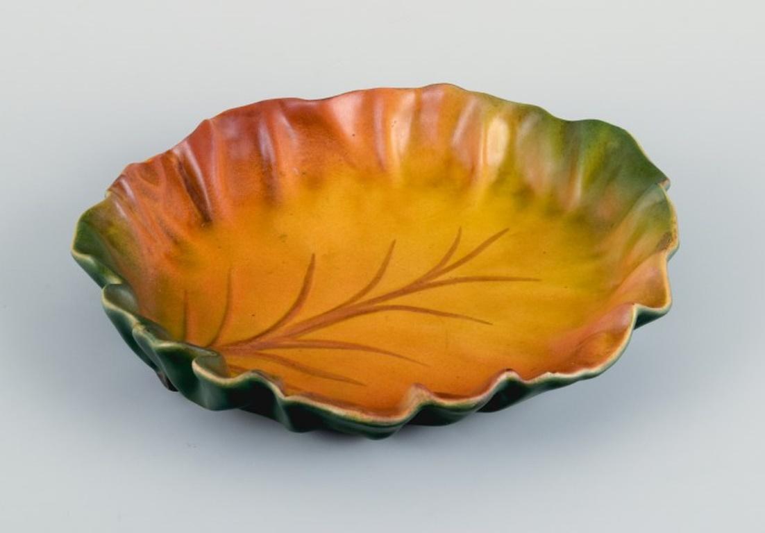 Ipsens, Denmark, leaf-shaped bowl. 
Glaze in autumn colours.
Model number 40.
1920s.
Marked.
In excellent condition.
Dimensions: D 20.5 x H 3.5 cm.
