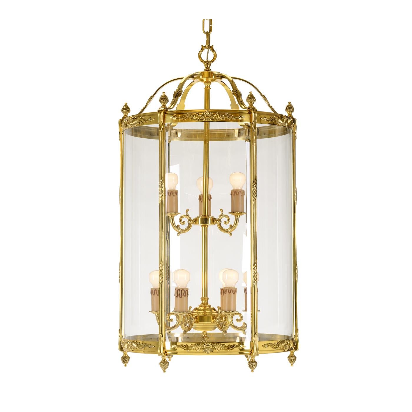 This elegant nine-light lantern was made in bronze with a French gold finish. Its cylindrical shape is enriched throughout by small decorations and the six sections of the cylinder are covered by transparent glass. Six sinuous arms support the