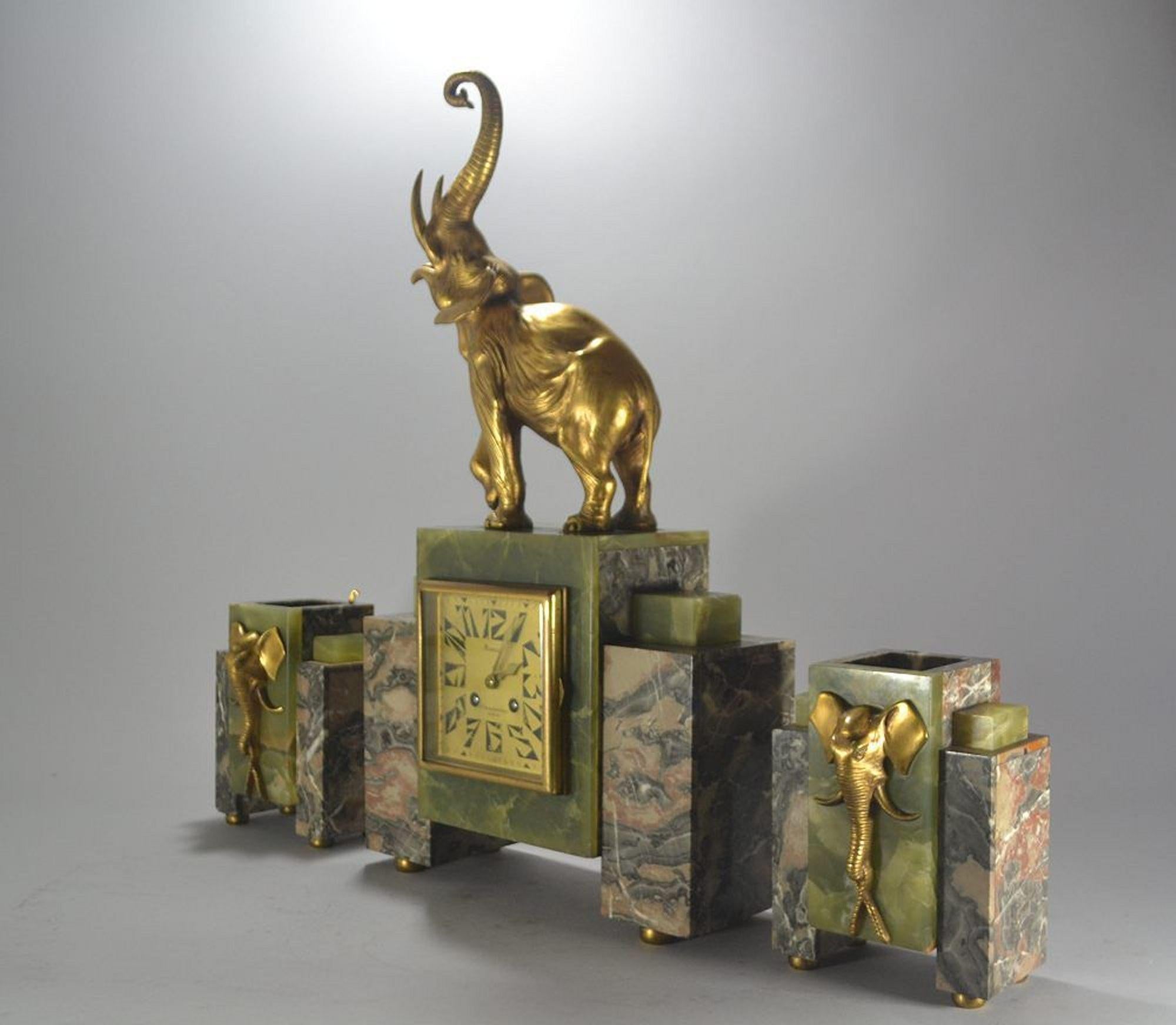 Irenee Rochard (1906-1984)

Circa 1930 impressive art deco clock.
Central piece is marble and onyx with gilt bronze elephant.
Signed to the marble and inscribed Reveyrolis Paris. (Editor).
Side vases are marble and onyx and hold two gild bronze