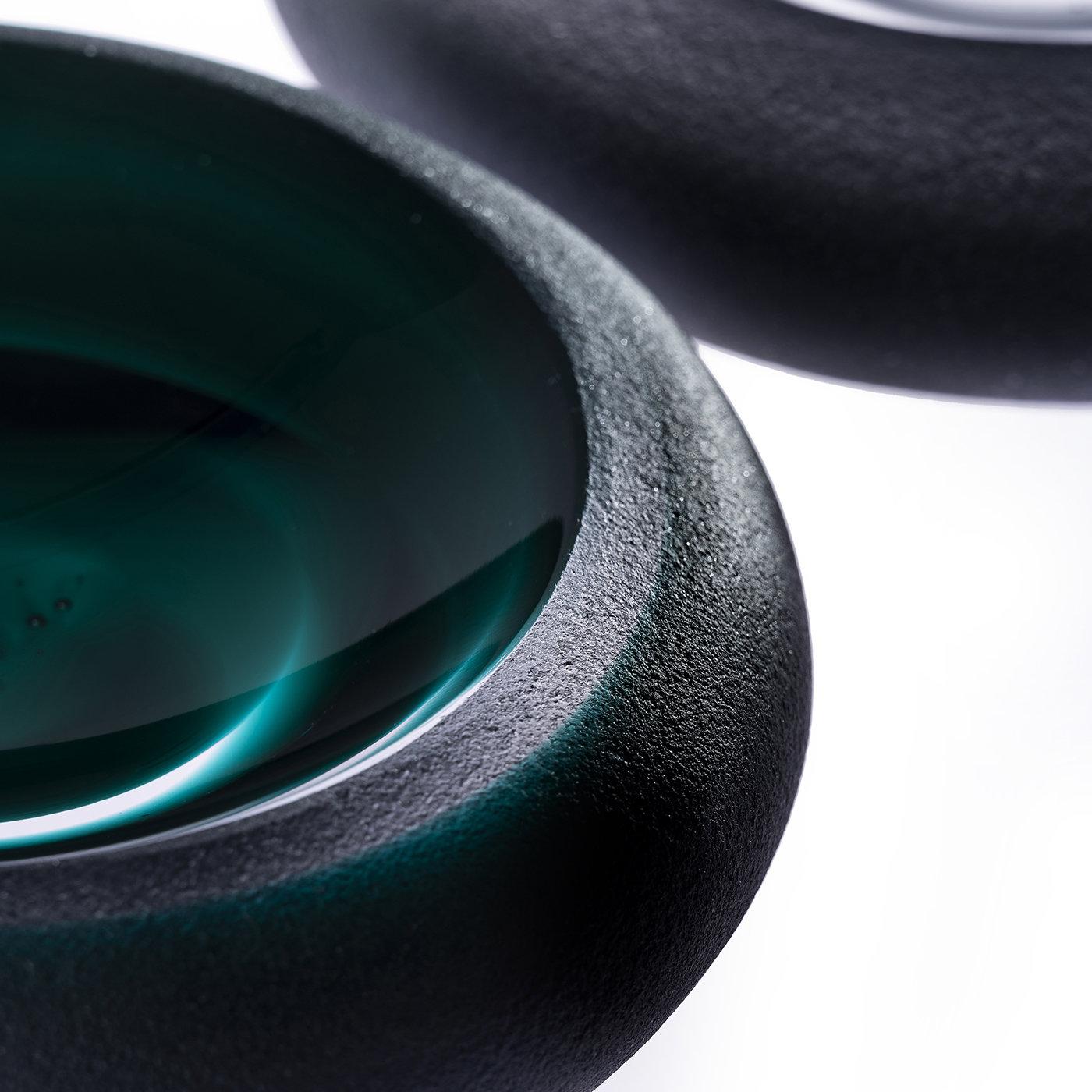 The Iride Sand Ashtray in Emerald Green features coarse sandblasting on the outer surface for a unique finish. Almost resembling an eye in its design, the Iride collection is comprised of three different circular models, all crafted with alternating