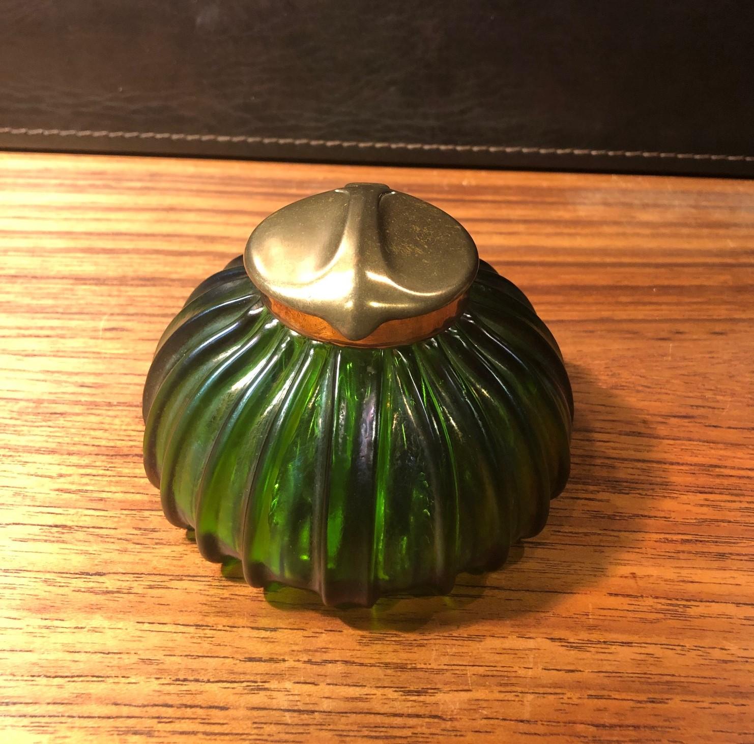 Stunning early Art Nouveau gourd shaped iridescent art glass inkwell, circa 1900s. The piece features a gorgeous array of rainbow iridescence from greens to golds to purples. The inkwell is capped with a gorgeous brass leaf motif lid and rim. Also